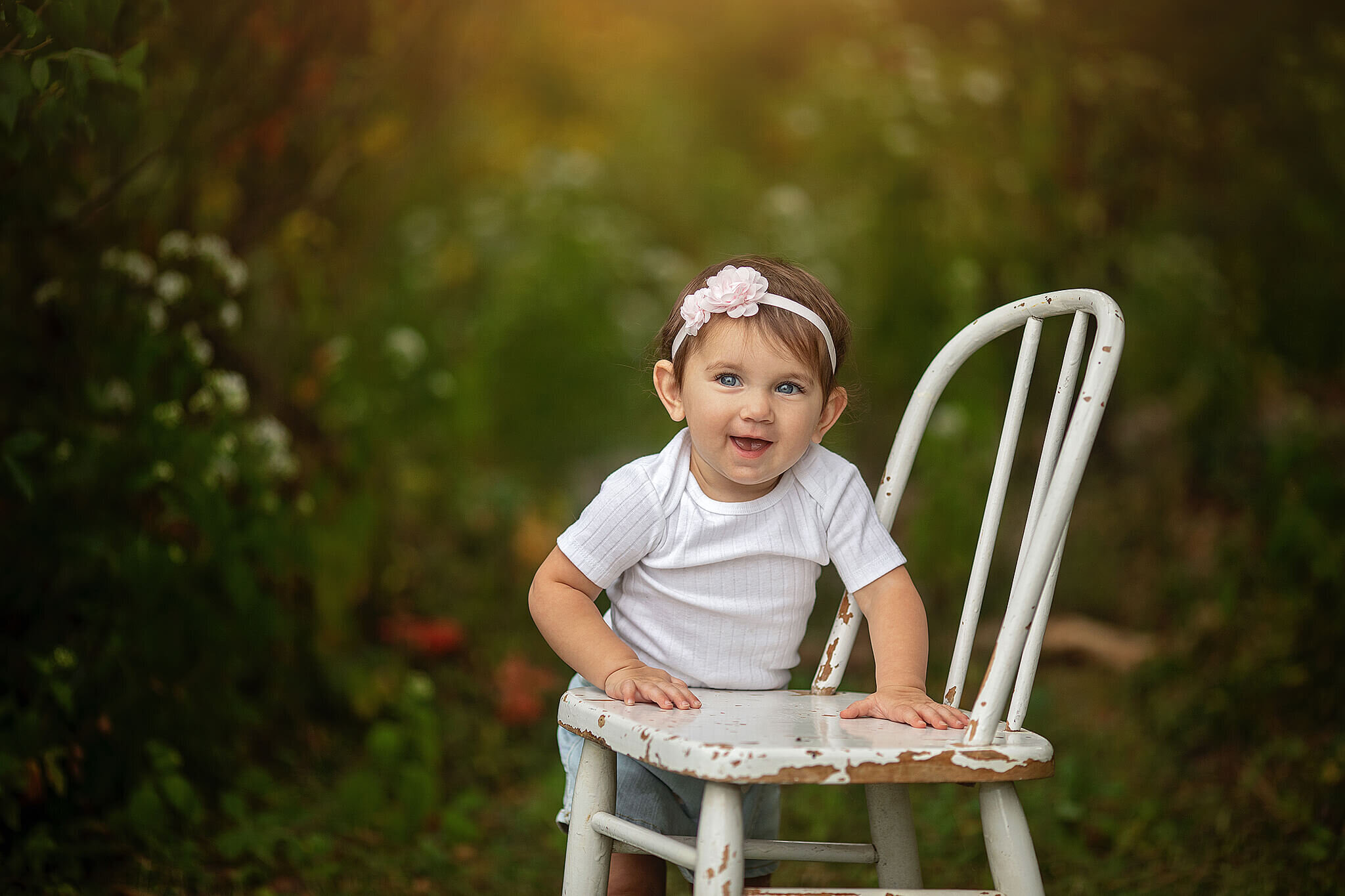 1  year old girl standing up against a chair outdoors
