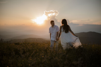 fallback shared on Invalid Date | Couple walks hand in hand in a wildflower field with sunset mountains in the background