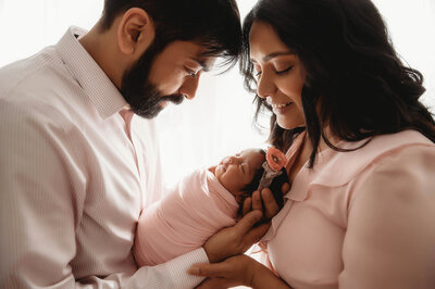 fallback shared on Invalid Date | New parents gaze at their infant during Newborn Photoshoot in Charleston, SC.