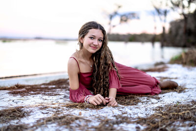 fallback shared on Invalid Date | Senior girl with beautiful long curly hair lays posing in sand along the shoreline of La...