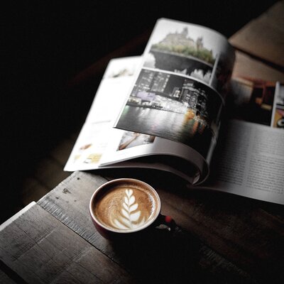 high-angle-view-coffee-by-magazine-table-against-black-background