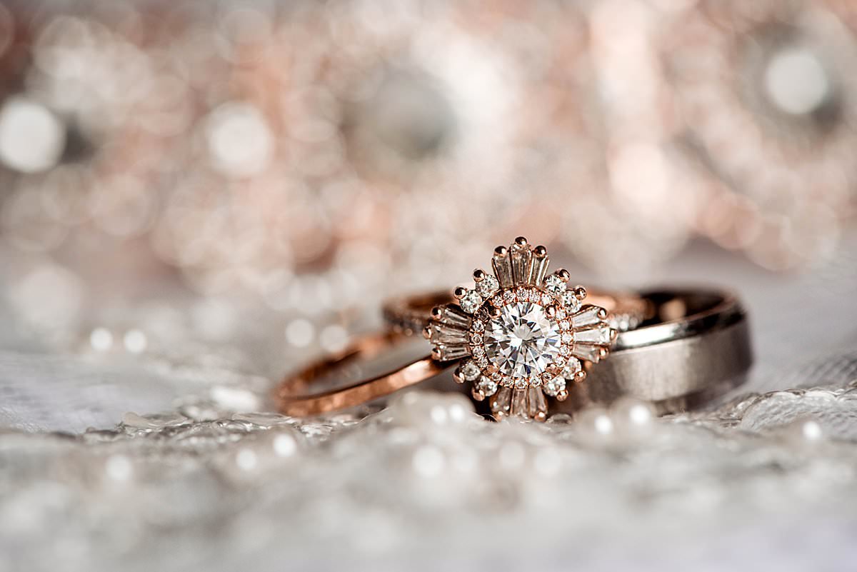 Detail photo of brides retro starburst rose gold wedding ring and grooms band