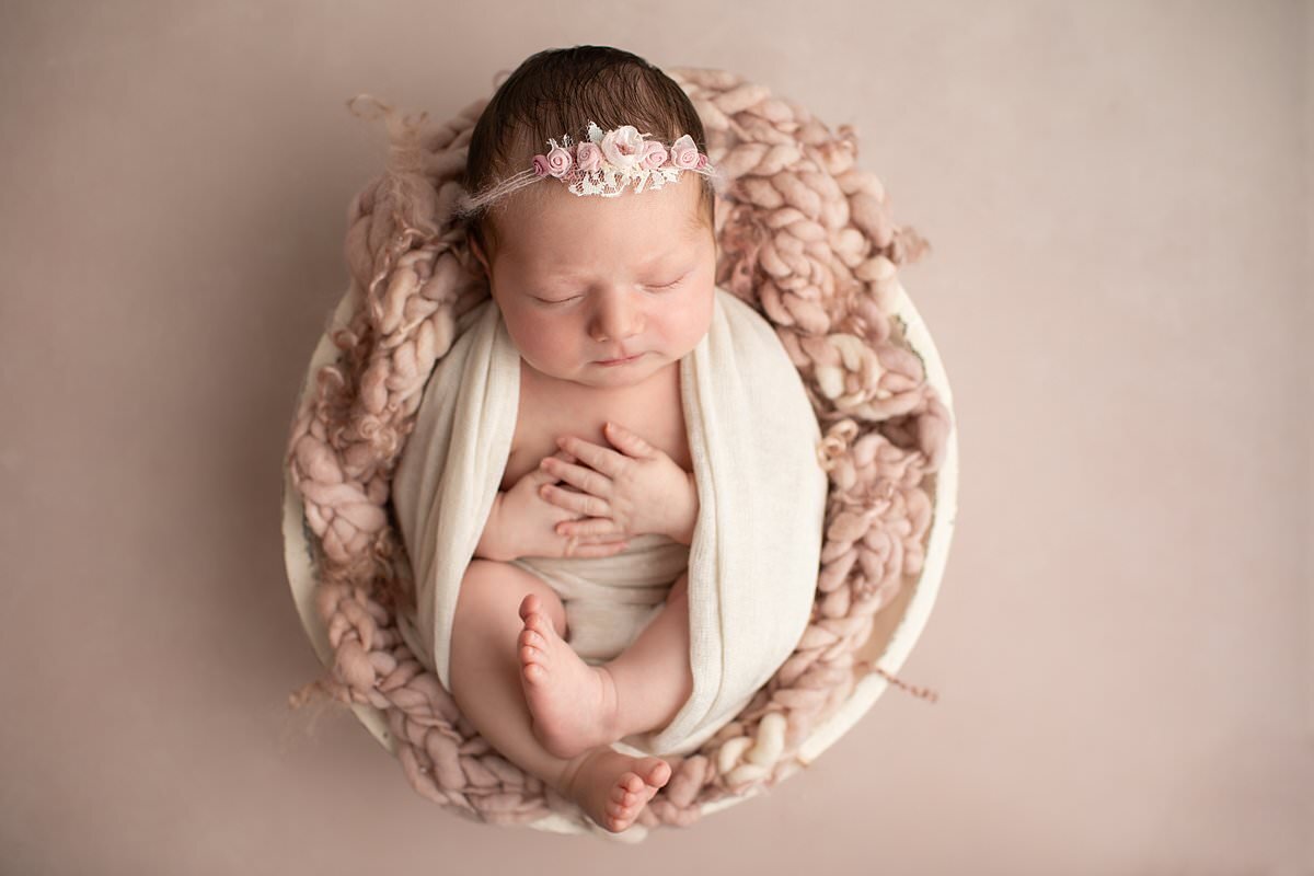 Baby girl wrapped in swaddle in basket with pink blanket for her newborn photography Columbia MD session
