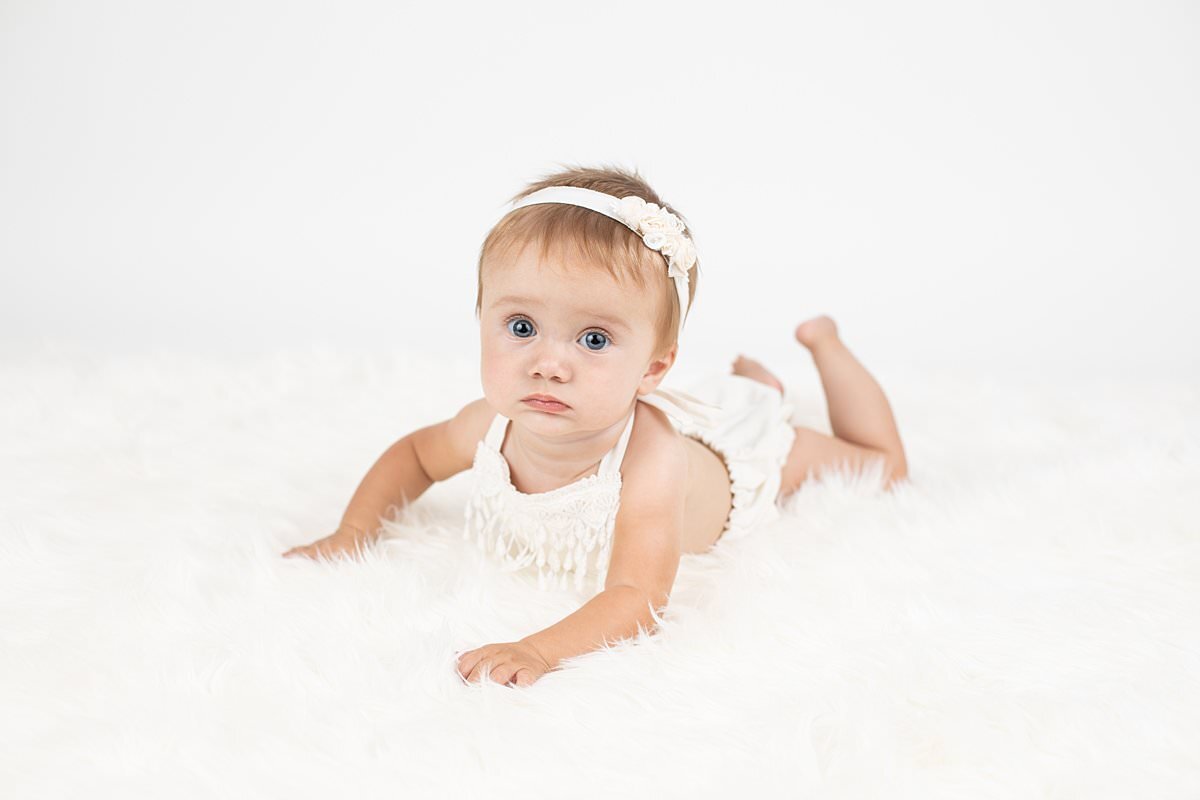 Baby girl laying on furry rug about to crawl for Maryland Portrait Photography session