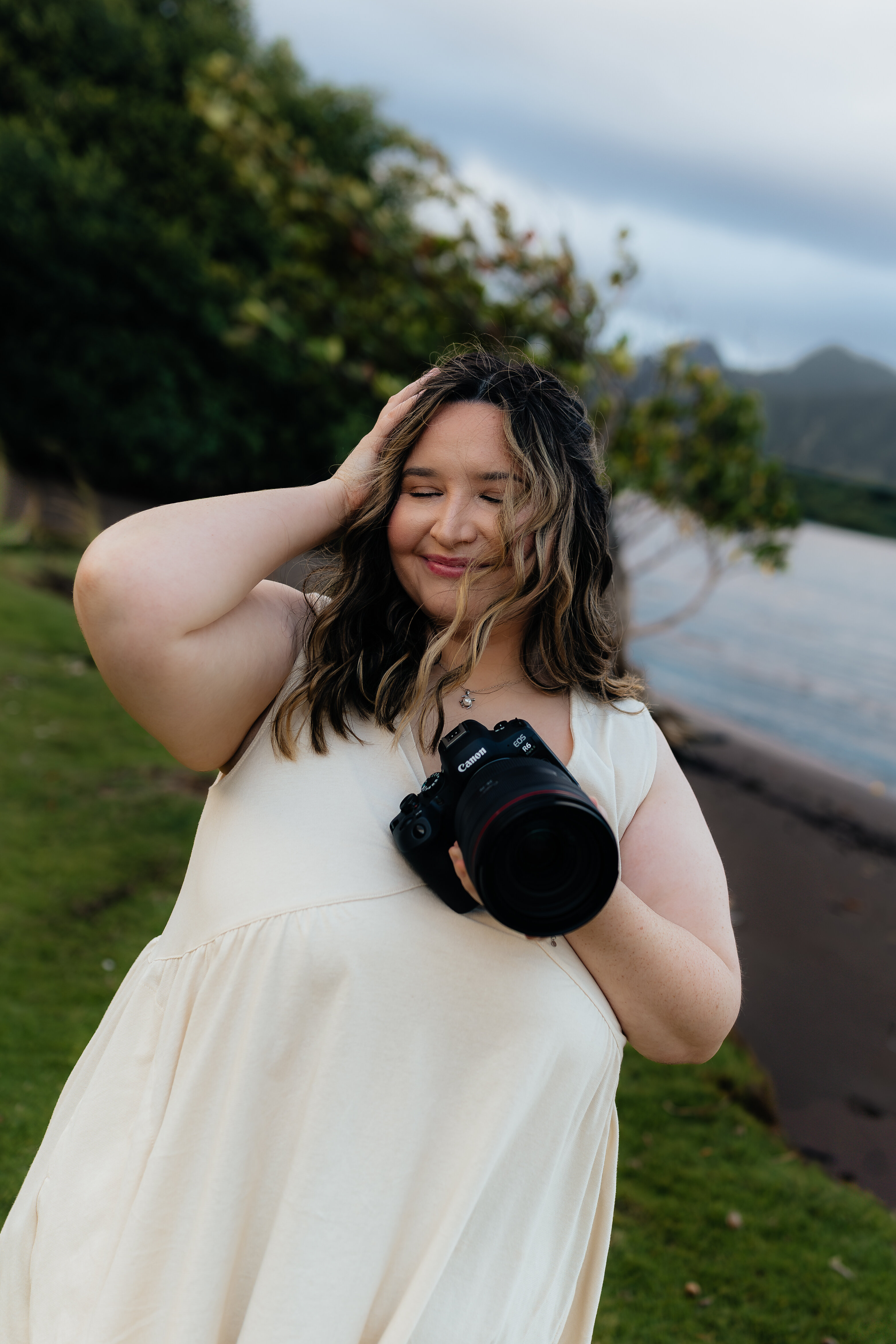 Close-up portrait of Oahu photographer in a cream dress with her camera