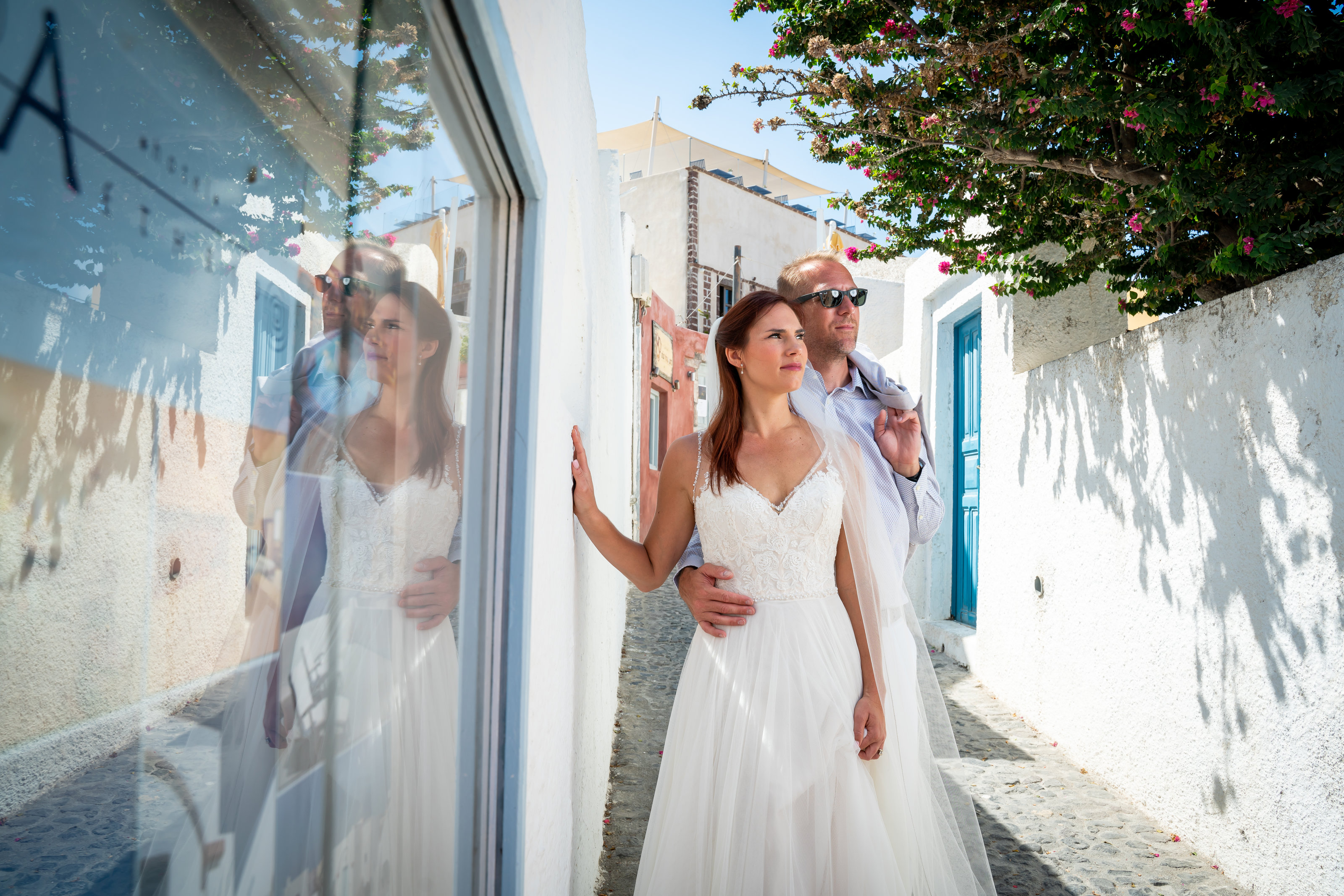 bride and groom standing looking away from the camera against a wall in santorini greece