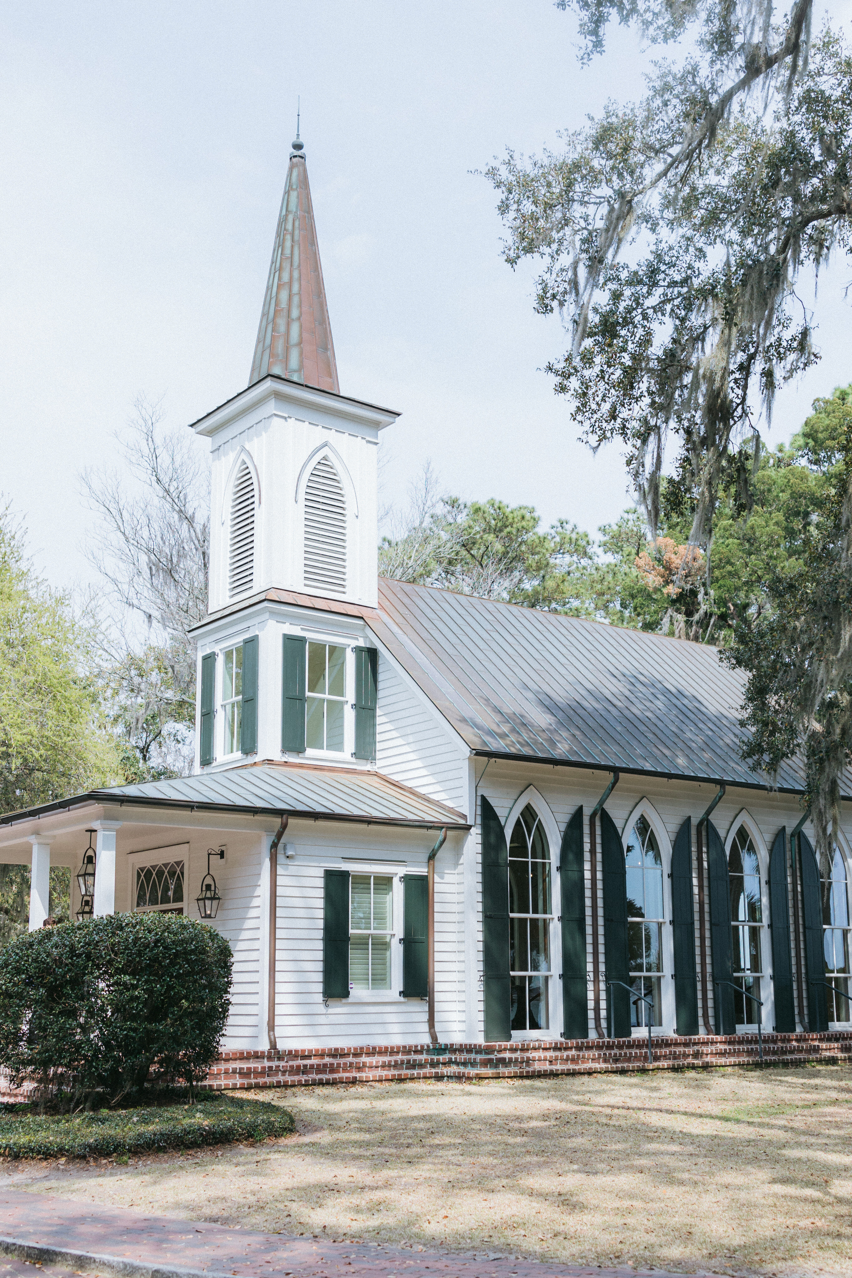 A charming white chapel surrounded by moss-draped oak trees at Palmetto Bluff, a picturesque venue for an intimate luxury wedding ceremony in South Carolina.