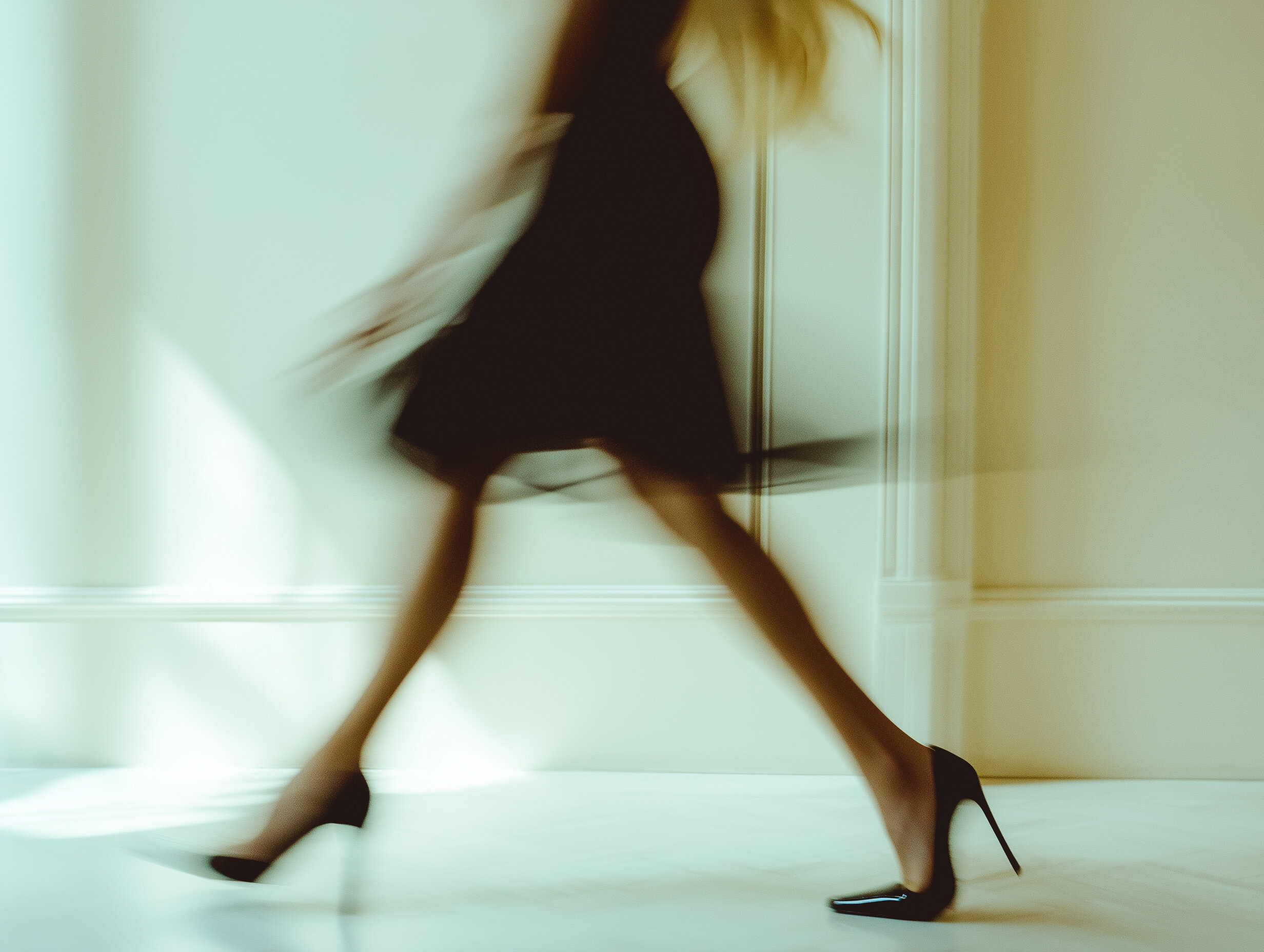 Motion blur photo of lower half of girl in black dress and heels walking fast