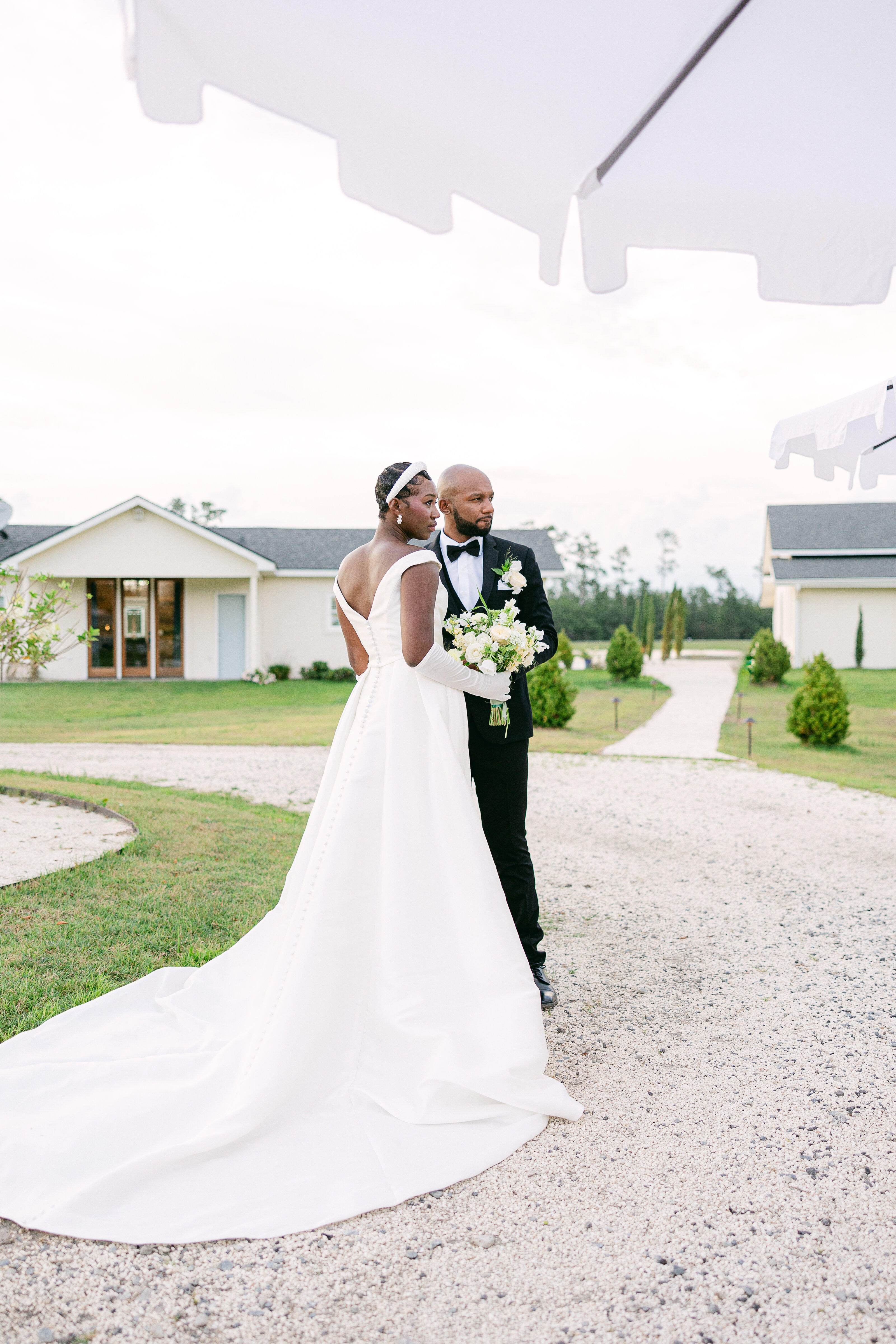 A sophisticated bride and groom pose at Chateau 1800 in Savannah, Georgia. The bride stuns in a classic off-the-shoulder gown with a flowing train, embodying timeless elegance.