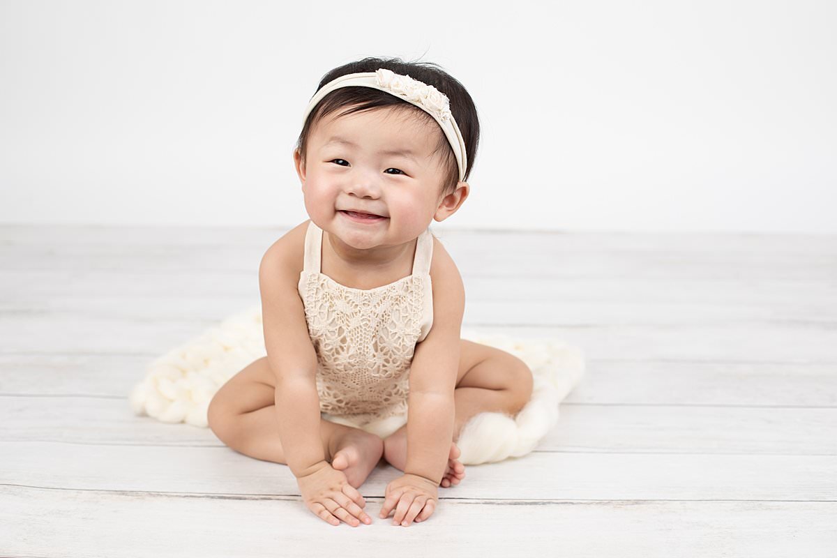 Baby girl wearing headband sitting and smiling for Maryland Portrait Photographer : Rebecca Leigh Photography