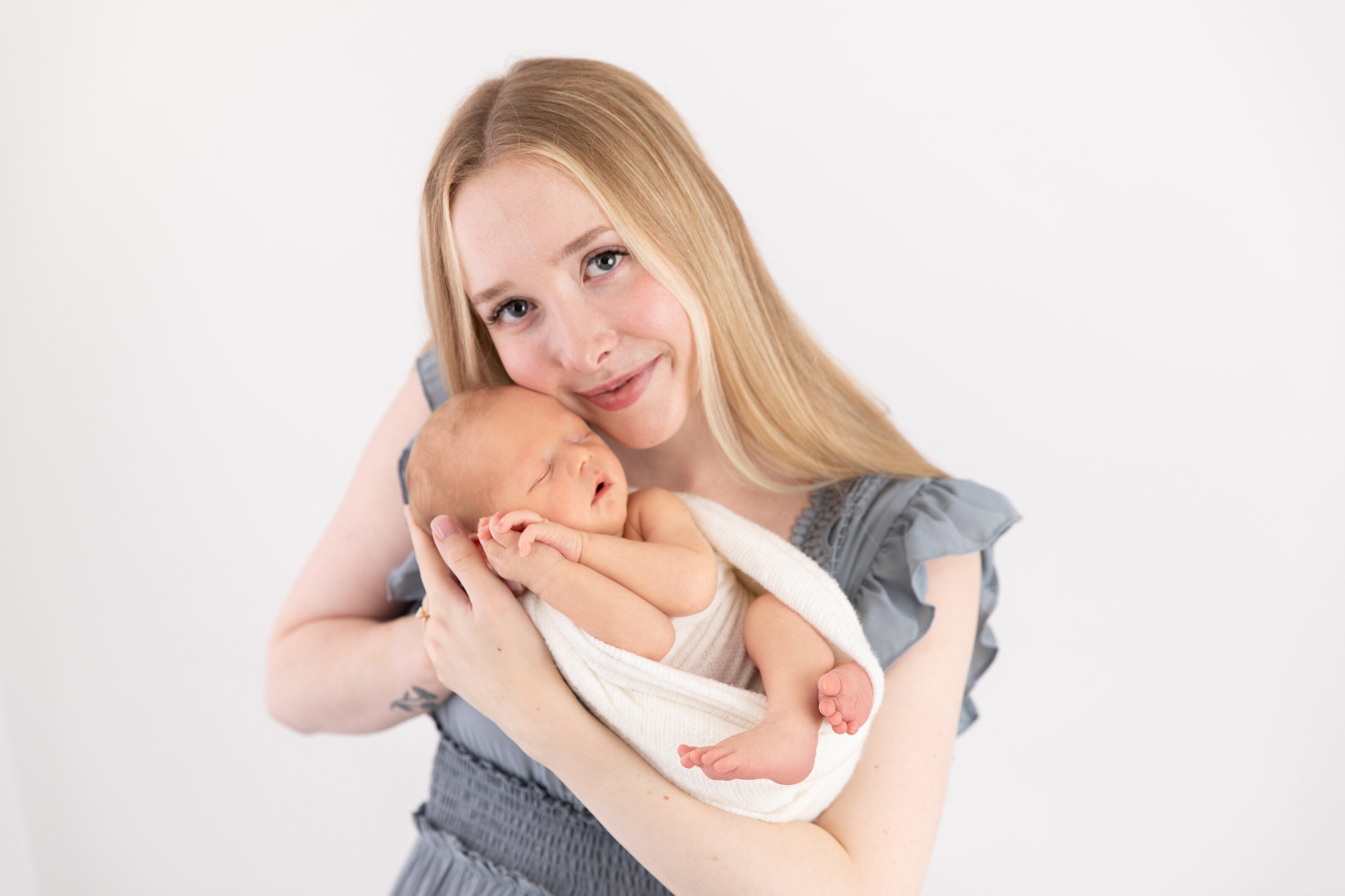 mother smiling at camera and holding newborn boy