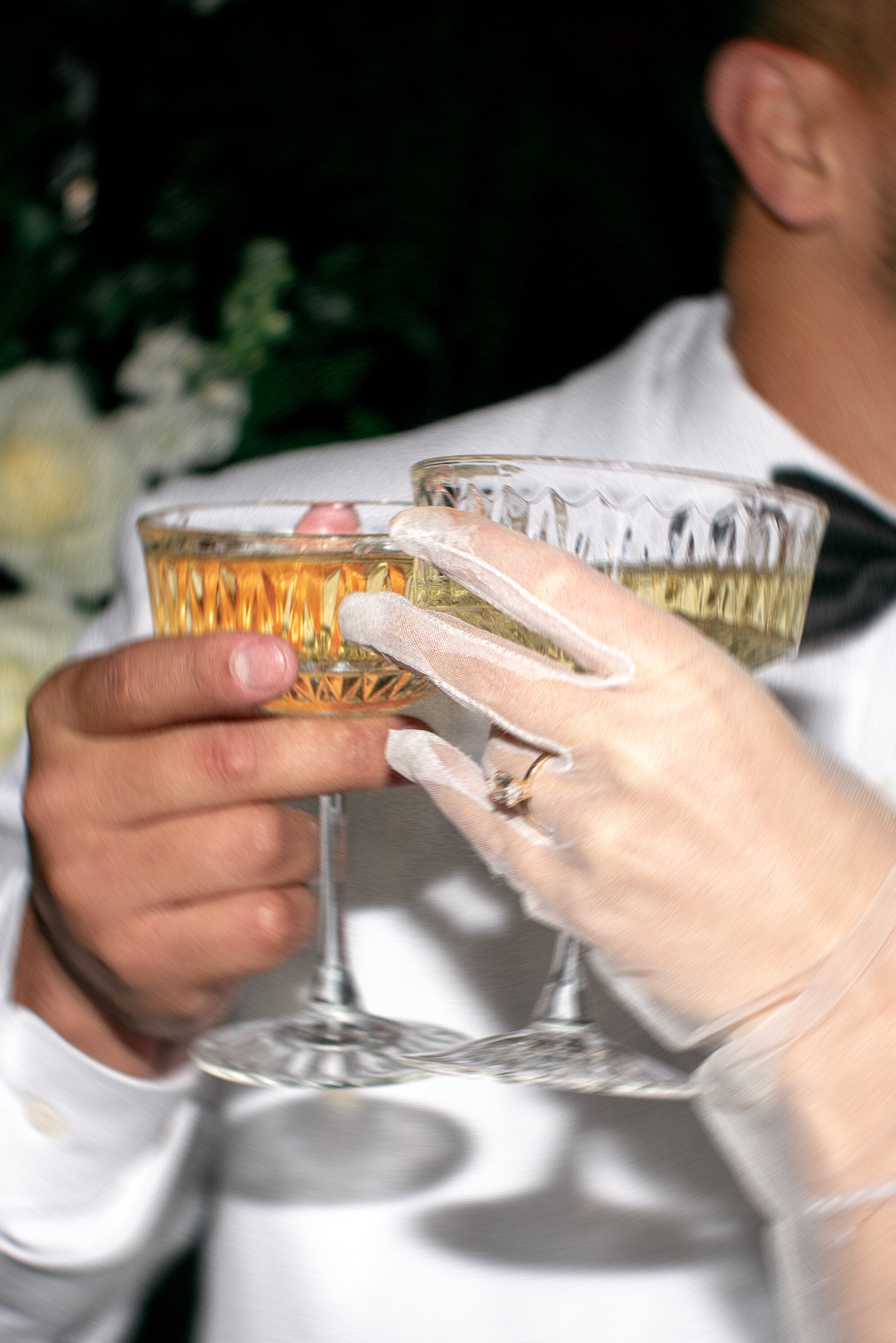 close up photo of two people holding champagne coupes and clinking them together