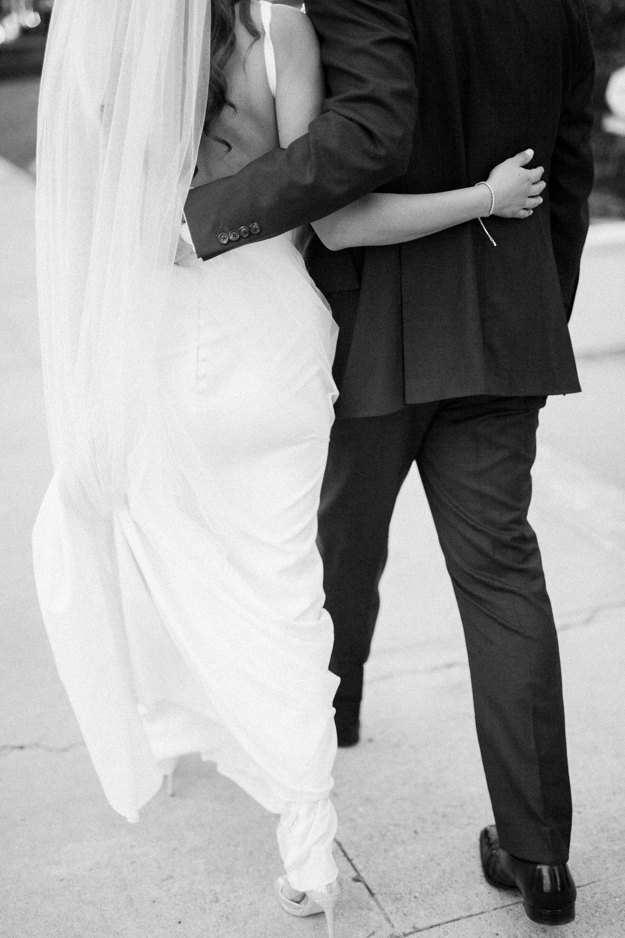 black and white photo of newlywed couple walking away with arms around each other