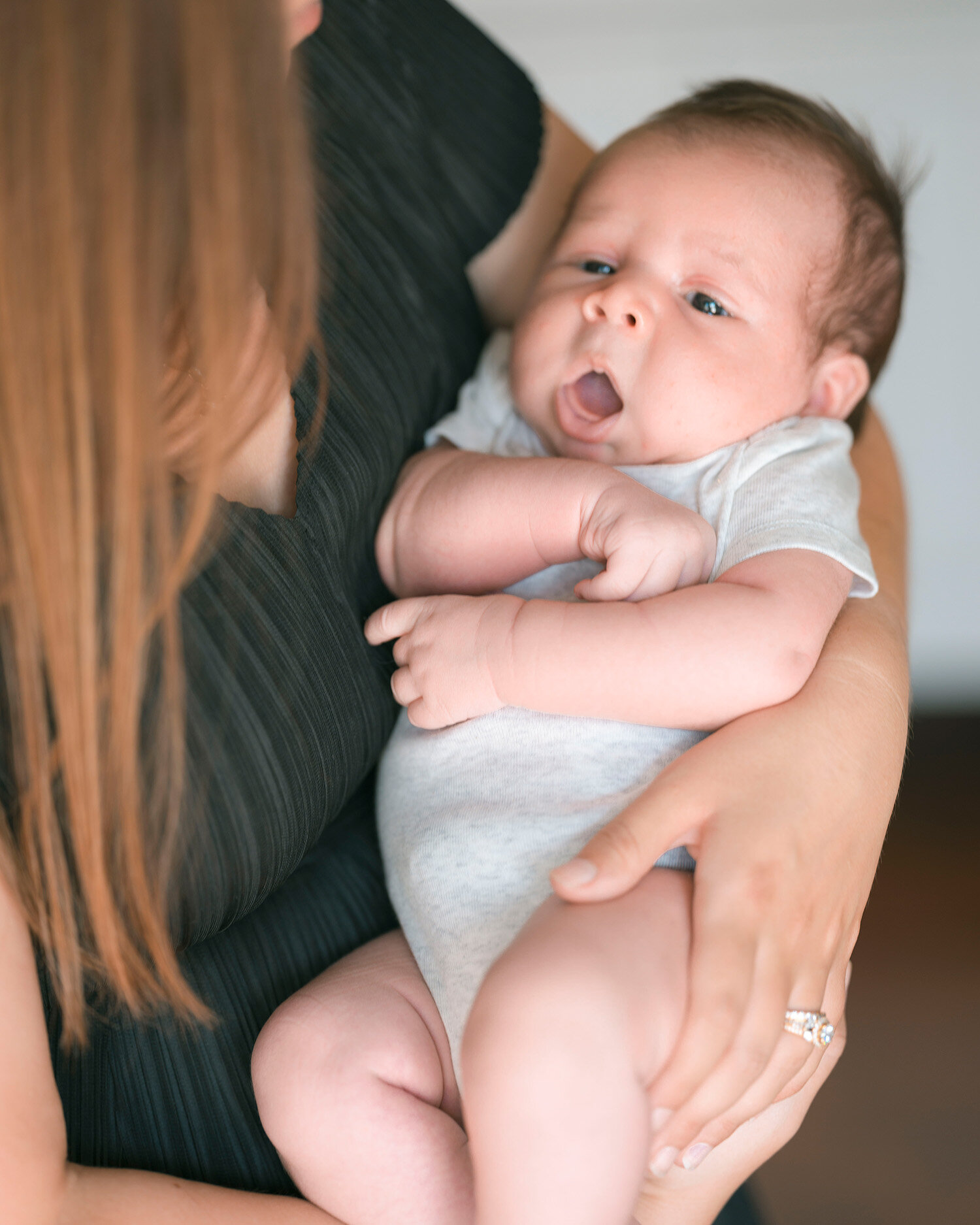 Mother holding newborn baby during a natural lifestyle session with San Francisco newborn photographer Isela Lozano, capturing authentic family moments in the Bay Area.