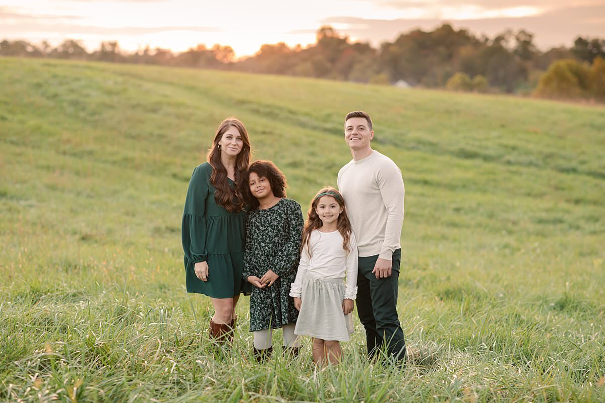 Family of 4 wearing green and cream outdoors in the grass for Maryland Family Photography session