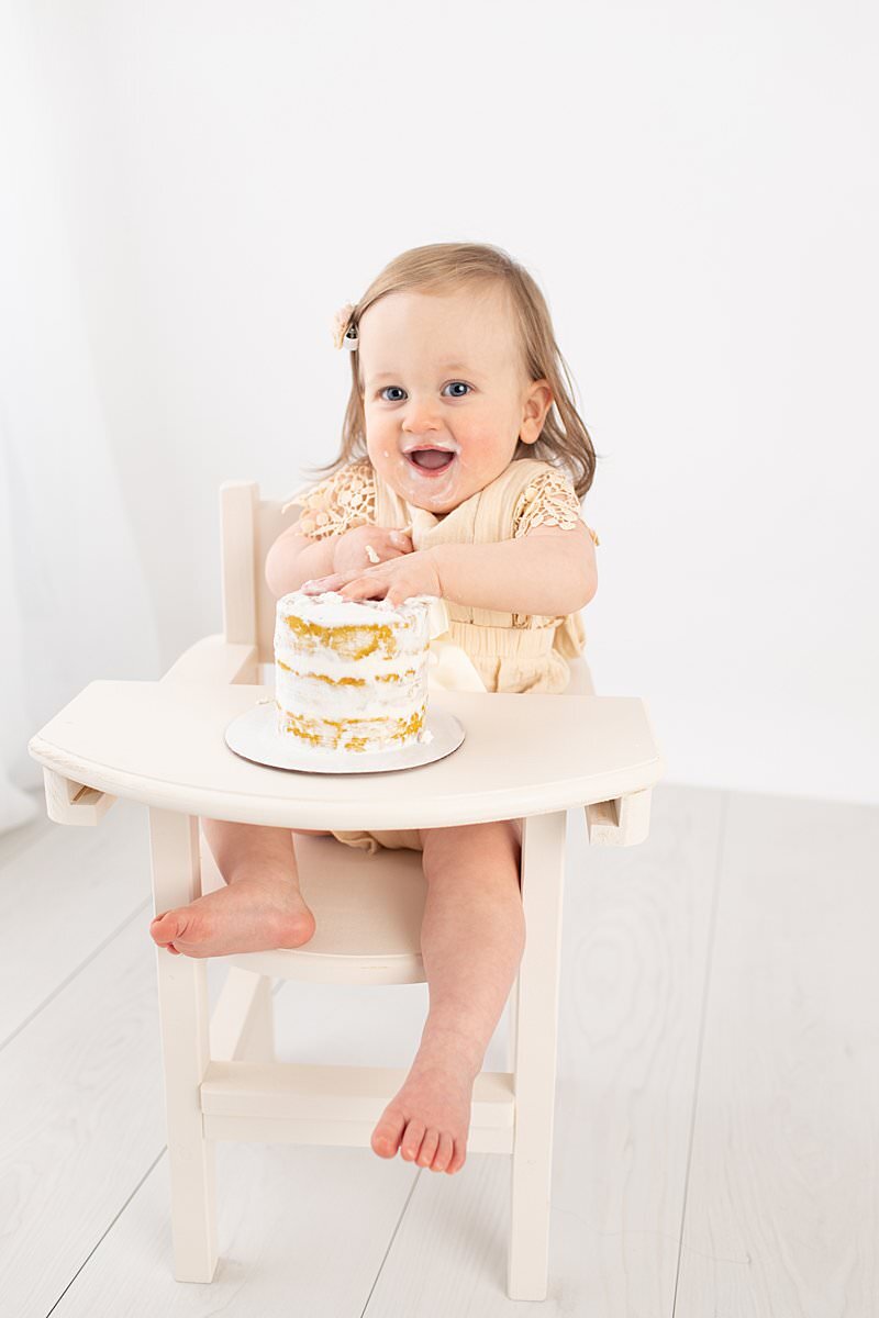 Baby girl smiling at camera during her smash cake session by Maryland Portrait Photographer : Rebecca Leigh Photography
