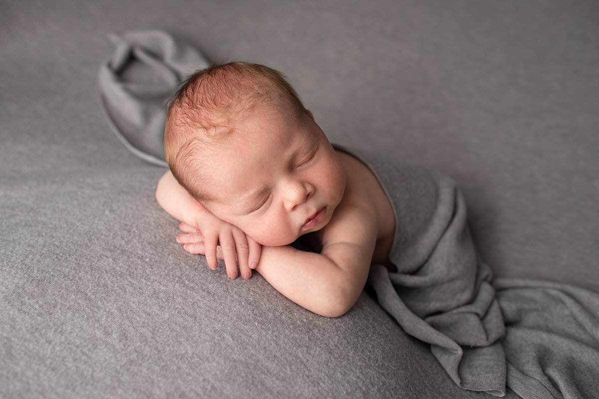 Baby boy sleeping in newborn pose with gray blanket by Baltimore Newborn Photographer