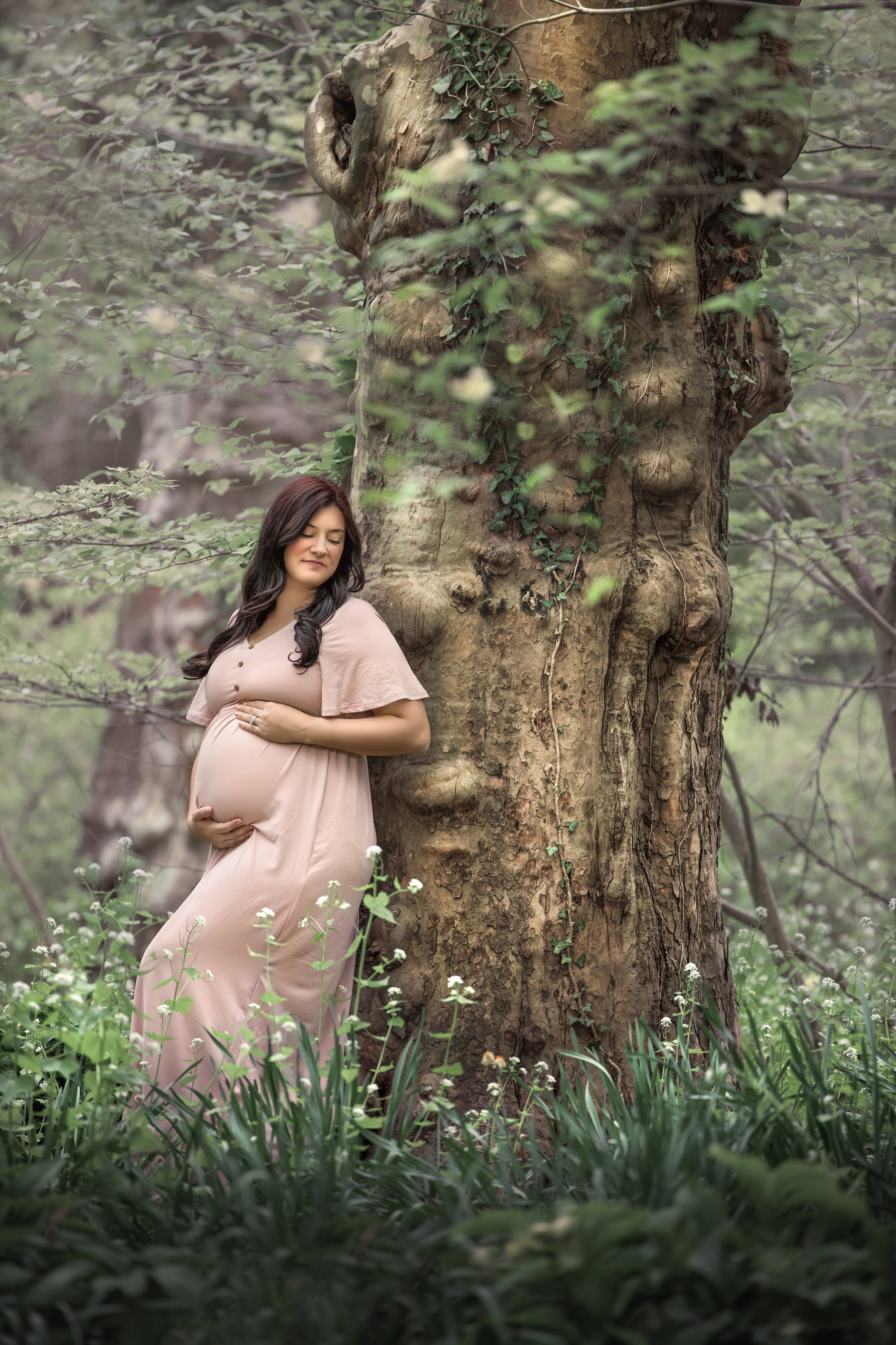 Pregnant woman hols belly for photos during maternity photography session at Sayen Gardens in Hamilton, New Jersey