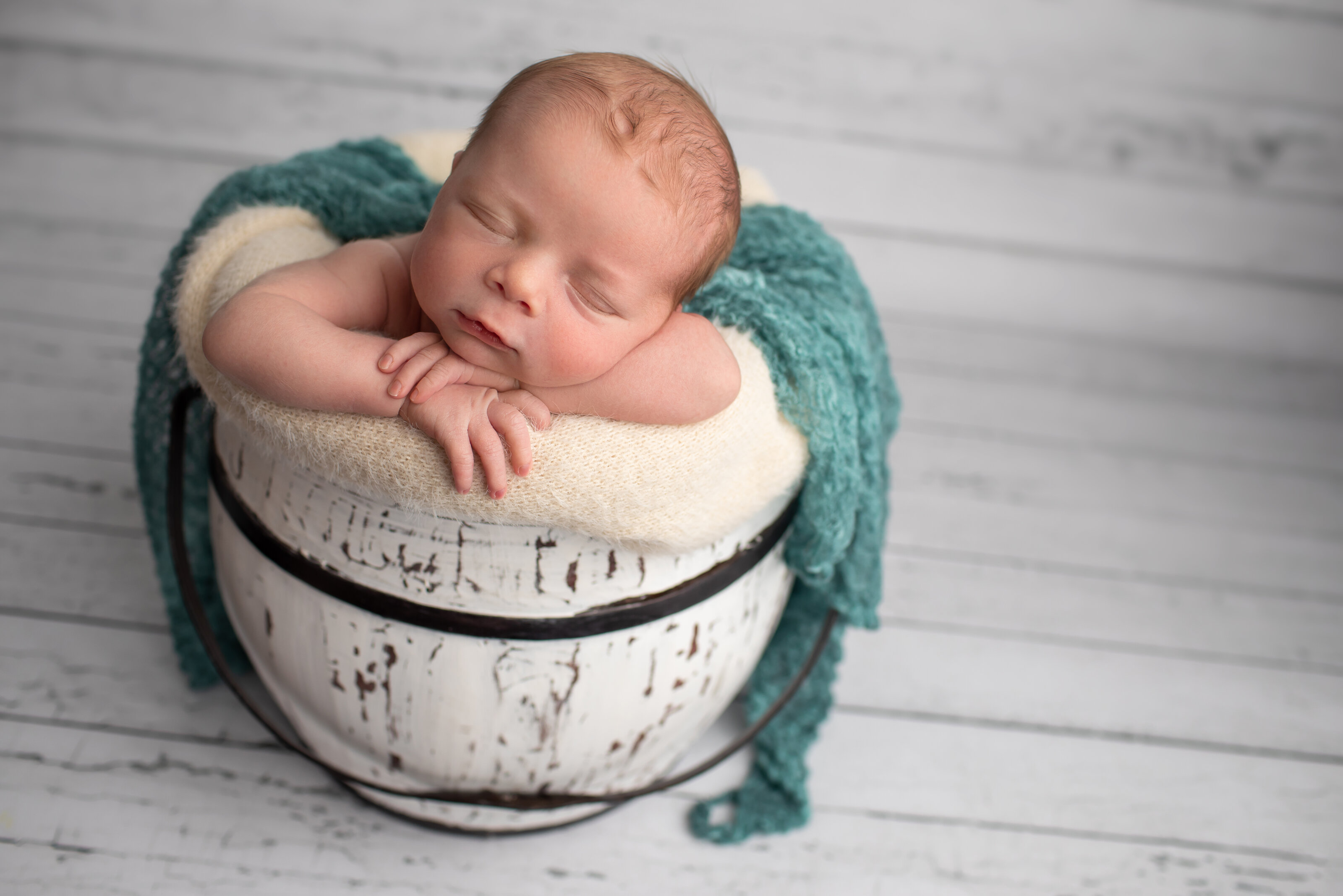 newborn boy sleeping in bucket pose