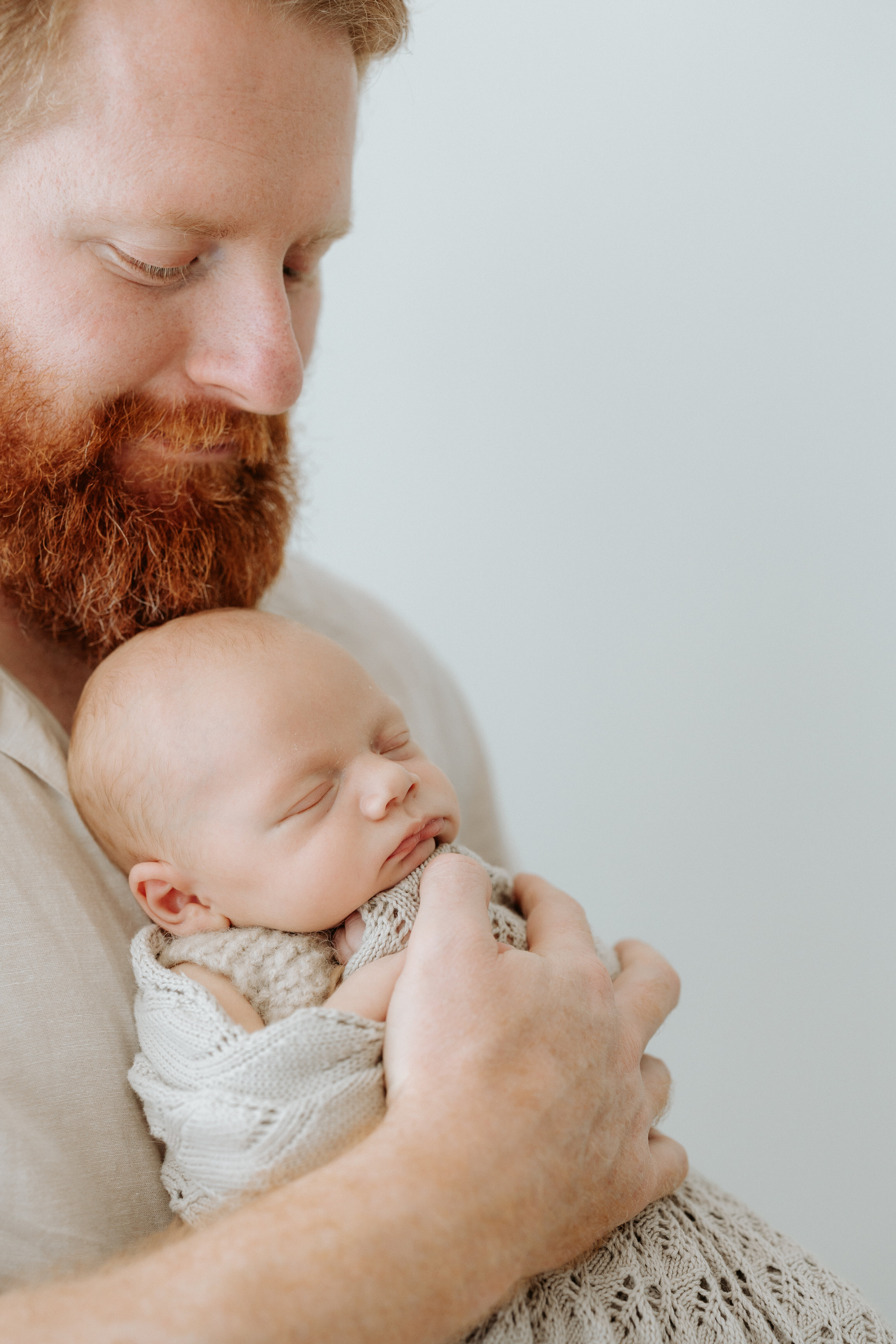 dad cradling newborn baby at indoor photography session in perth