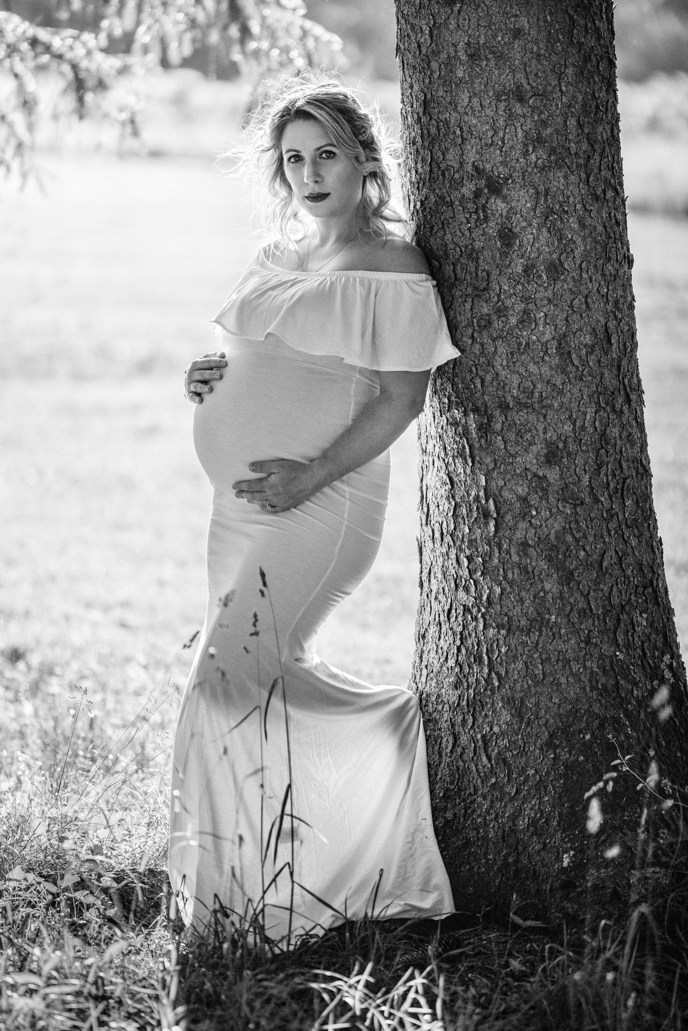 pregnant woman holds belly for maternity photos  at Veterans Park in Hamilton, New Jersey