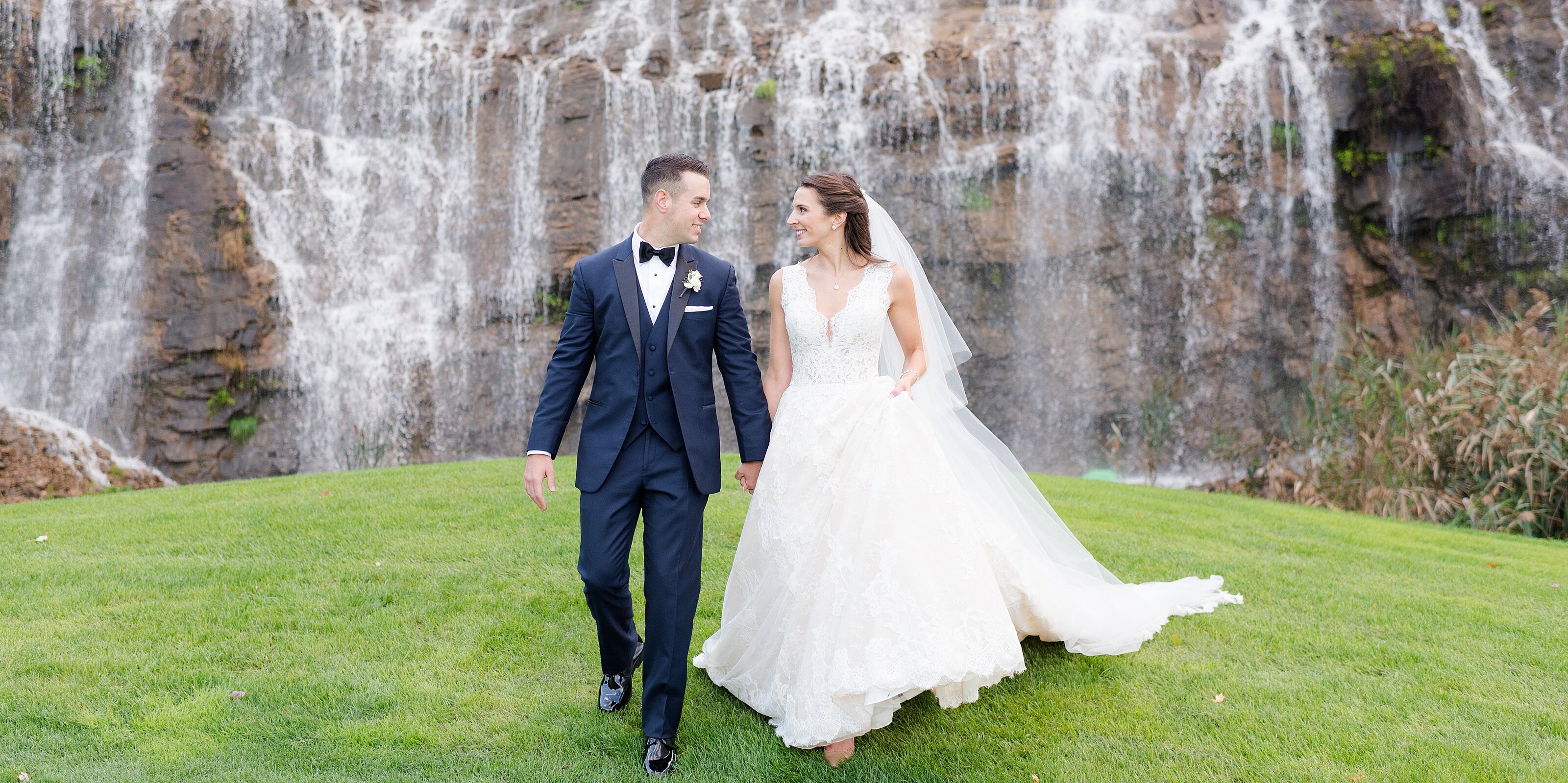 8_just-married-couple-walks-with-a-waterfall-behind-them
