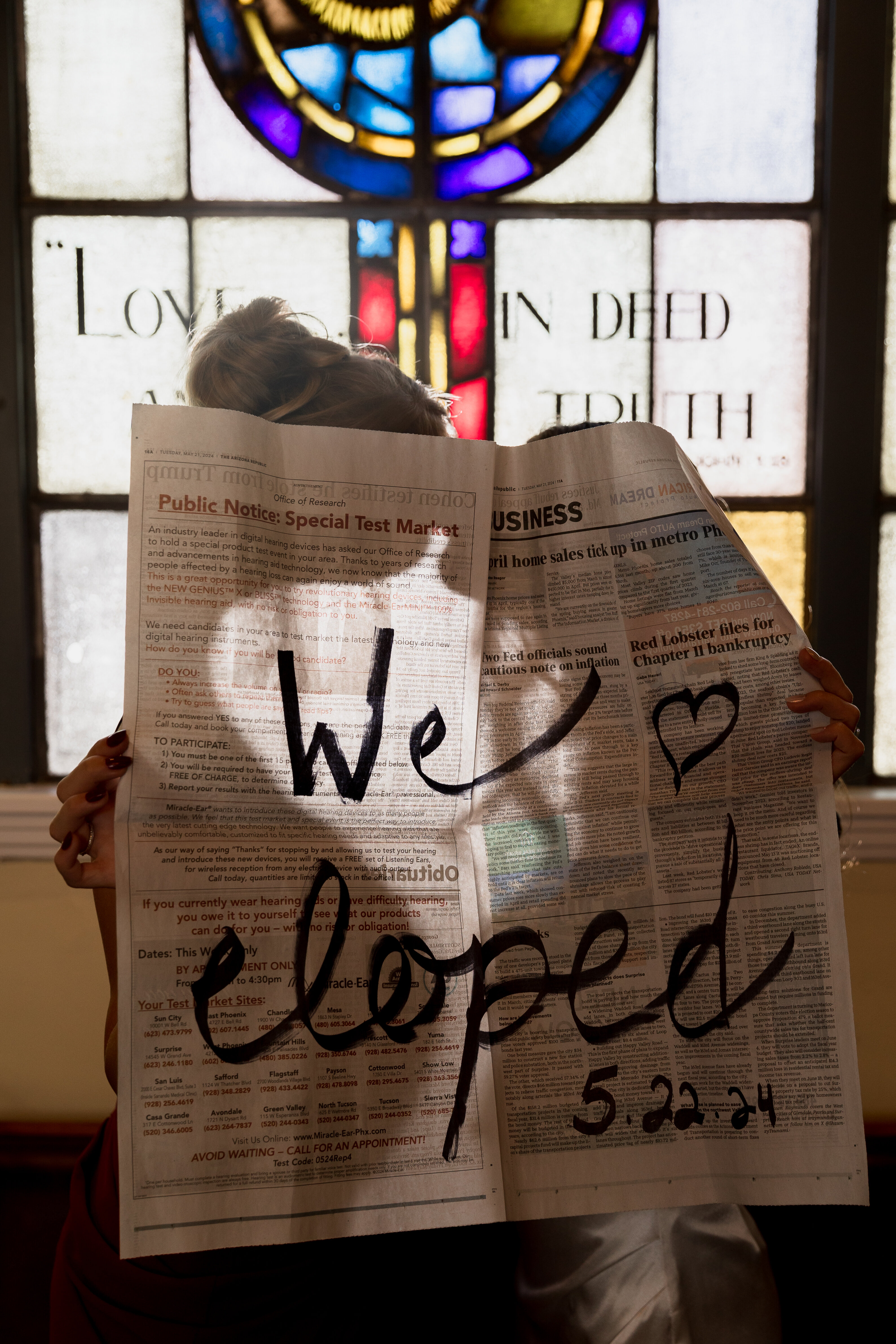 photo of a lesbian couple staninding behind a newspaper that says we eloped