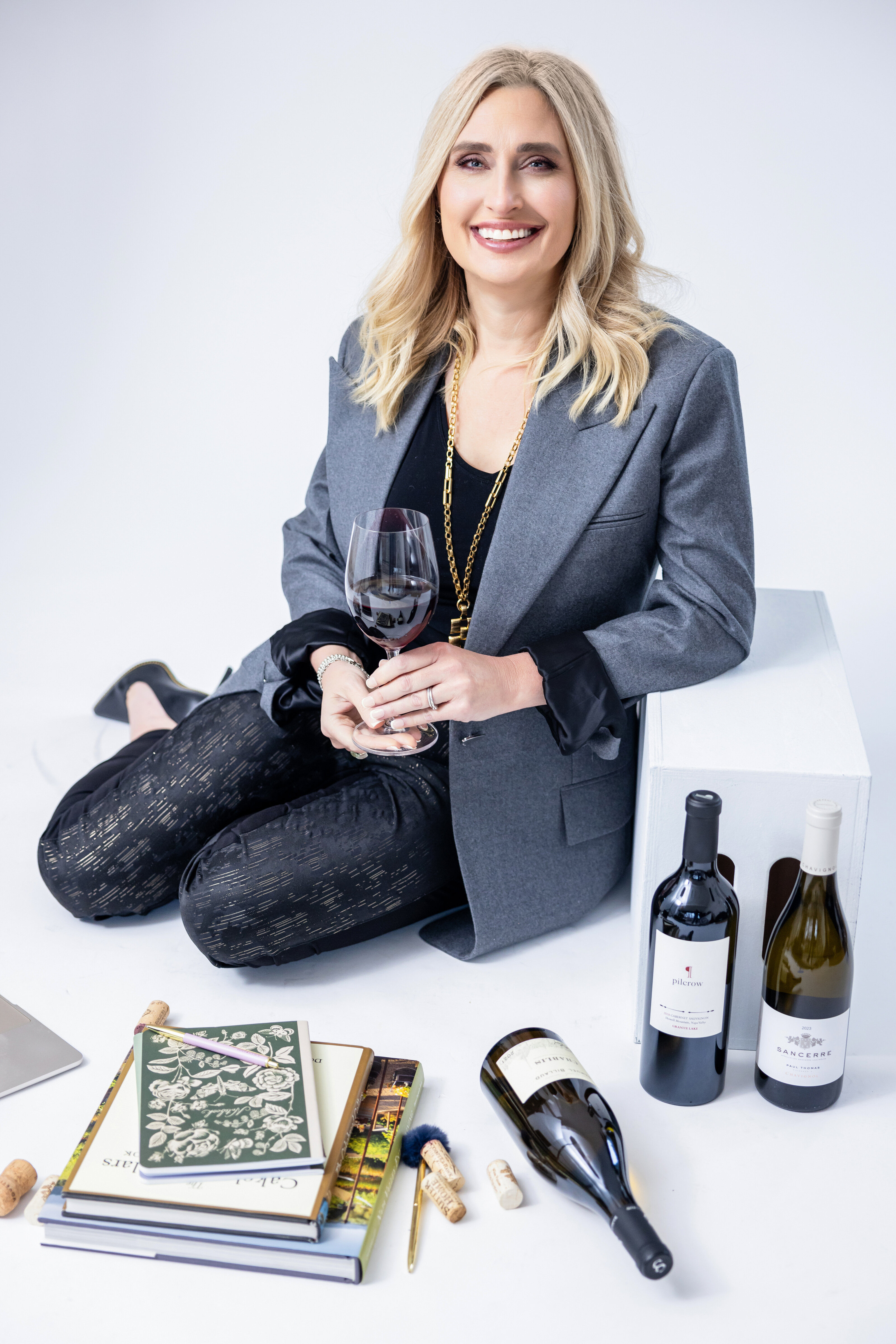 A woman holds a wine glass with her laptop in front of her