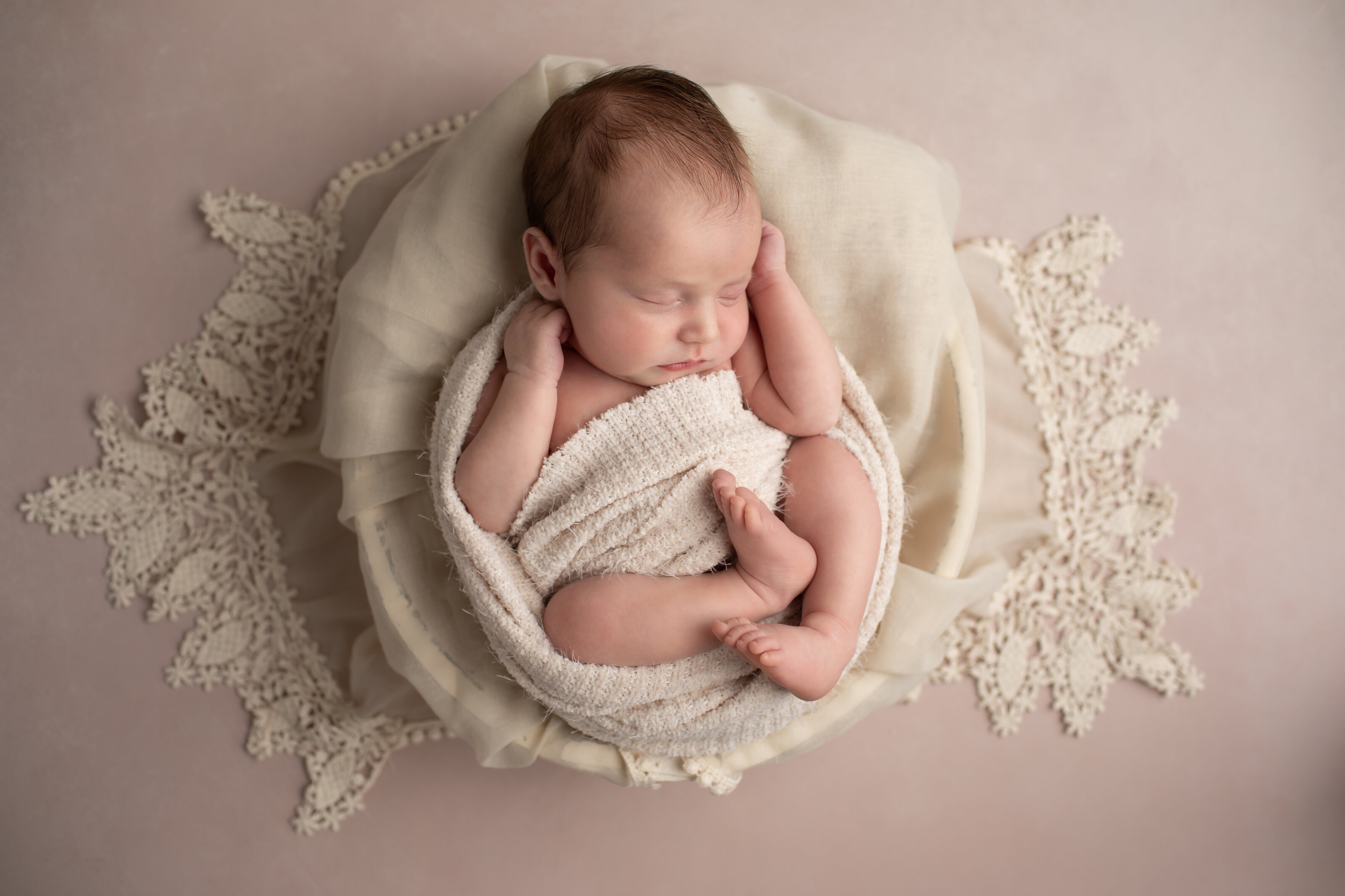 newborn girl sleeping in natural pose in bowl with lace on light pink background in Ellicott City Maryland