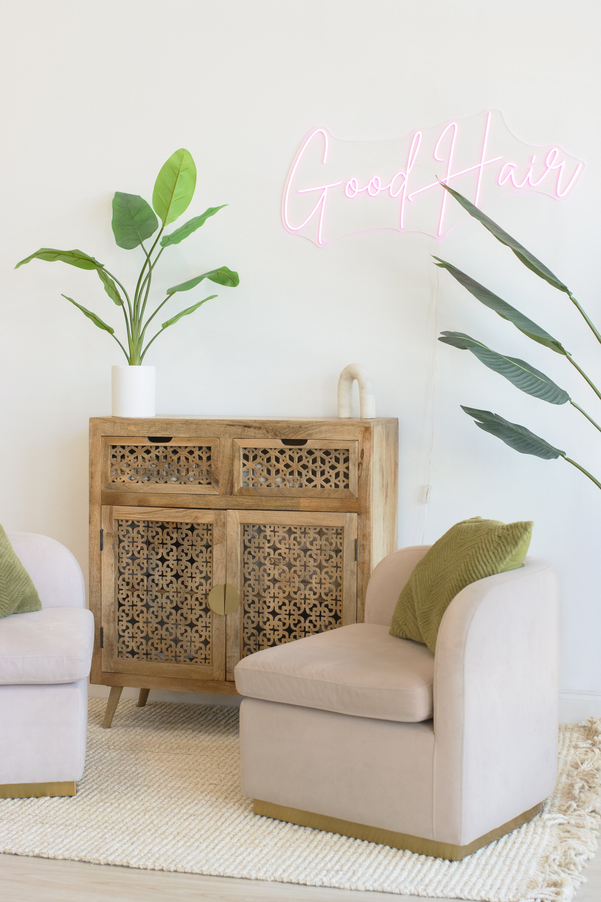Hair salon waiting area featuring chairs and a neon sign that says “good hair”