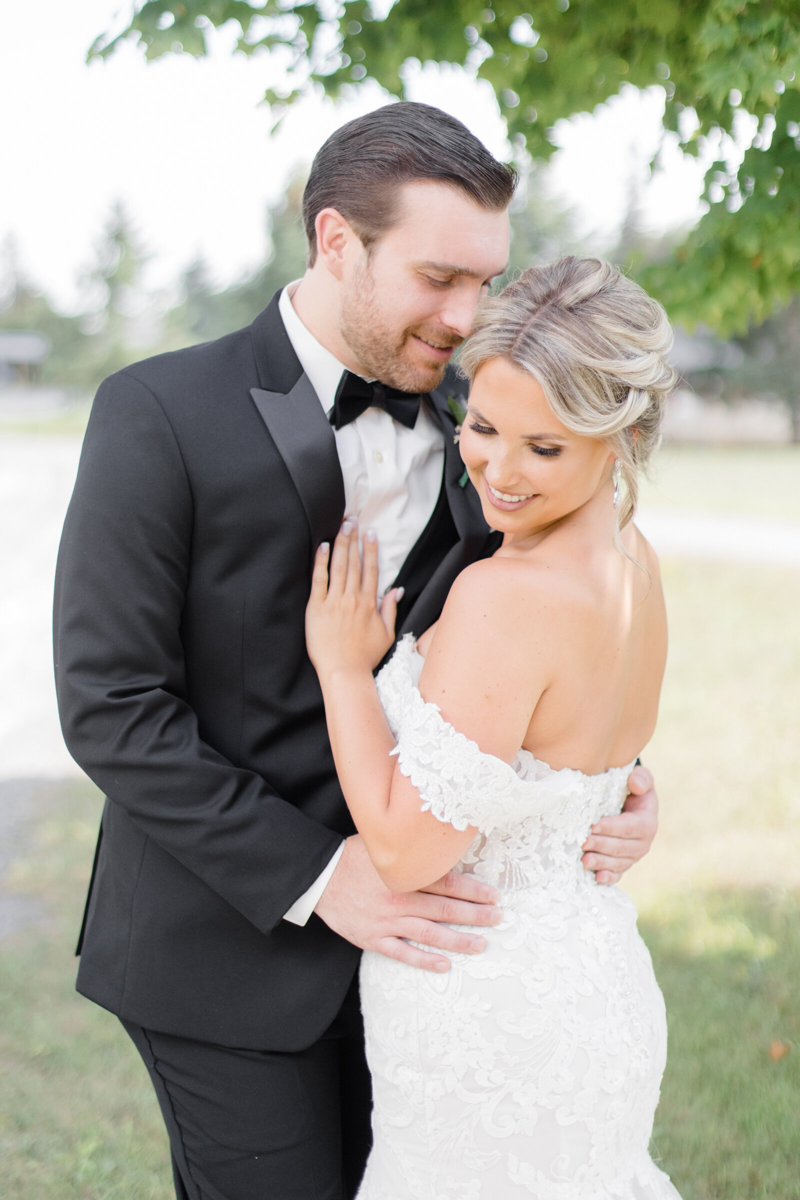 Bride and groom wedding day picture, with the groom in a black tuxedo, bride in a lace gown