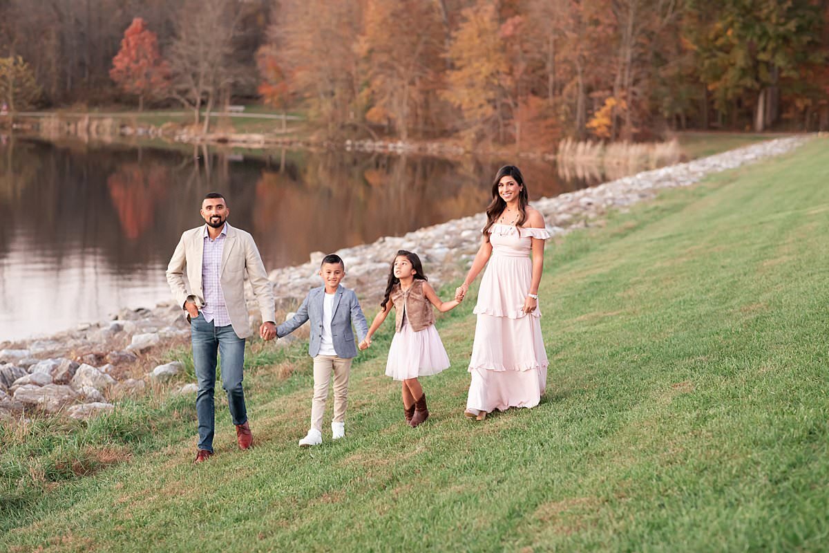 Family of 4 walking on grass by lake at Outdoor family session for family of 4 by Maryland Family Photographer