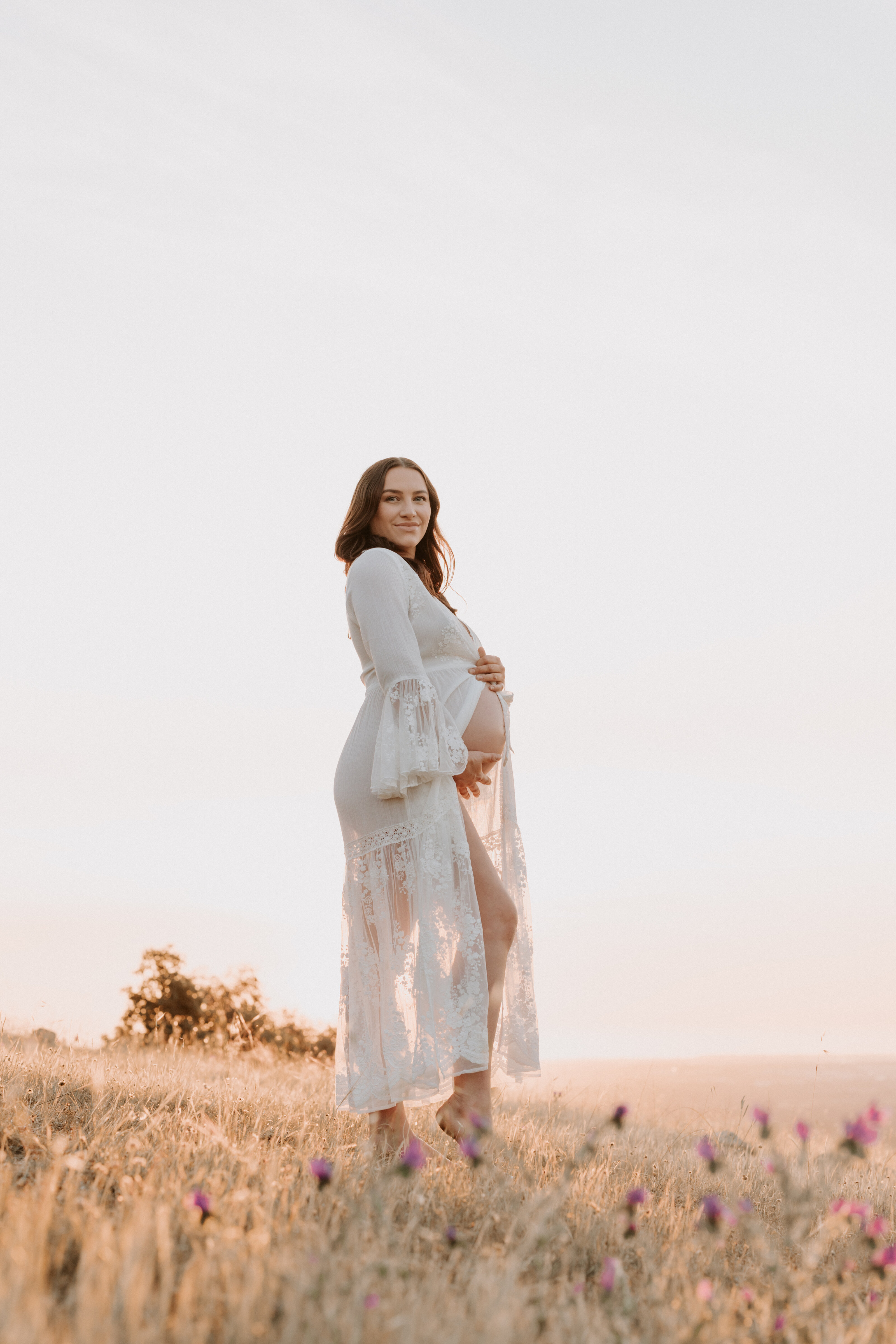 Expecting mother standing in soft golden light during an outdoor maternity session in Perth