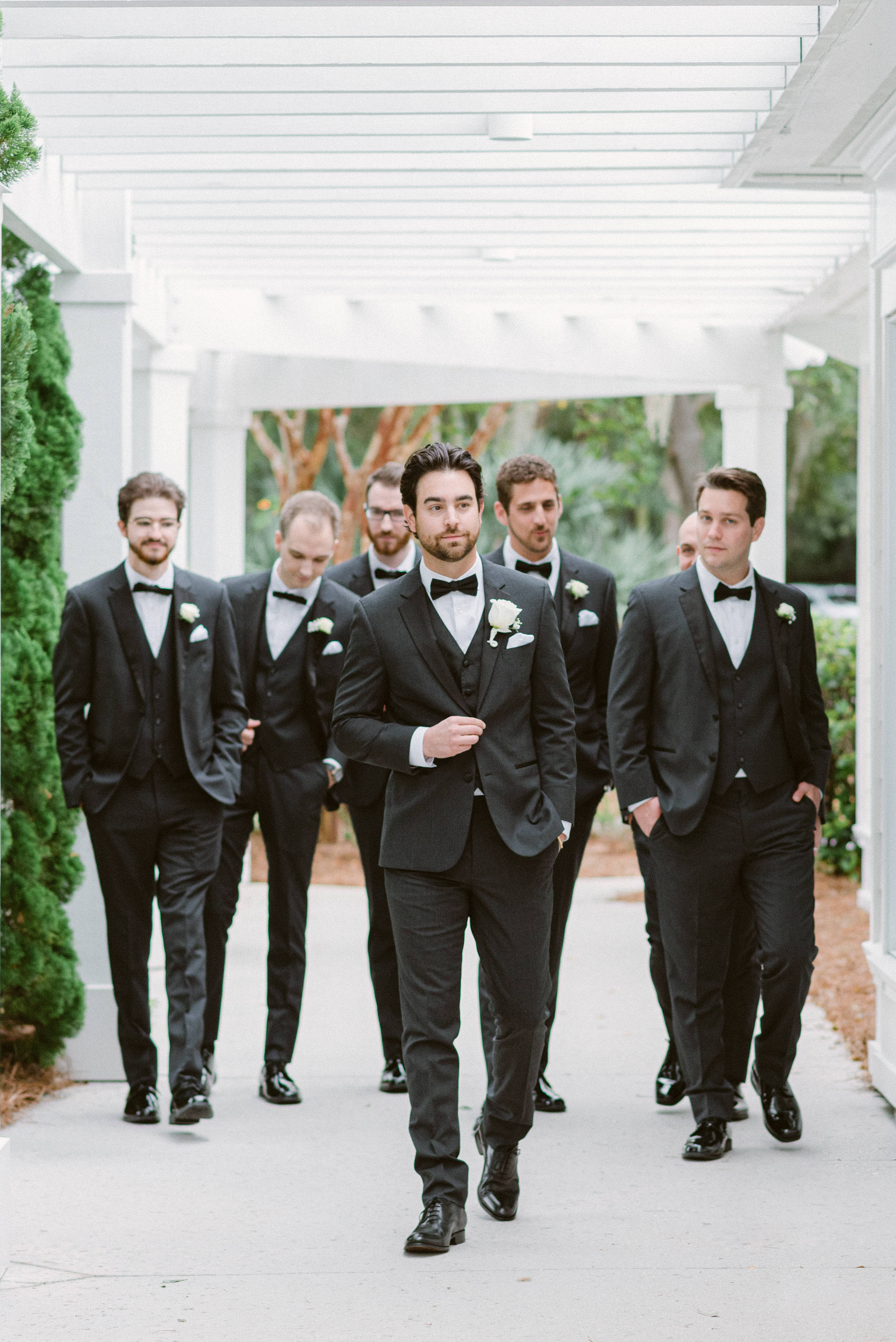 A groom leads his groomsmen in classic black tuxedos at a luxury wedding in Sea Pines, Hilton Head Island. A sophisticated and stylish wedding party portrait.
