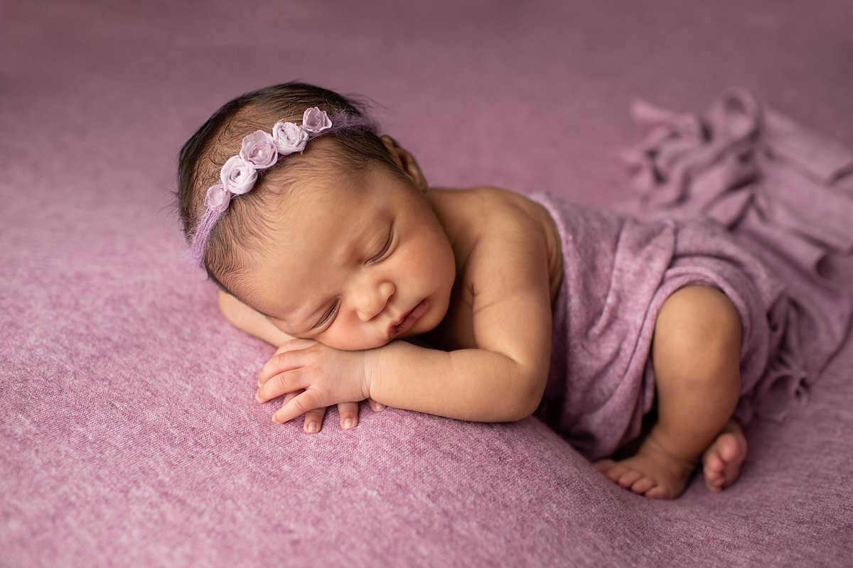 Baby girl in purple wrap sleeping on purple blanket for Columbia MD newborn photos