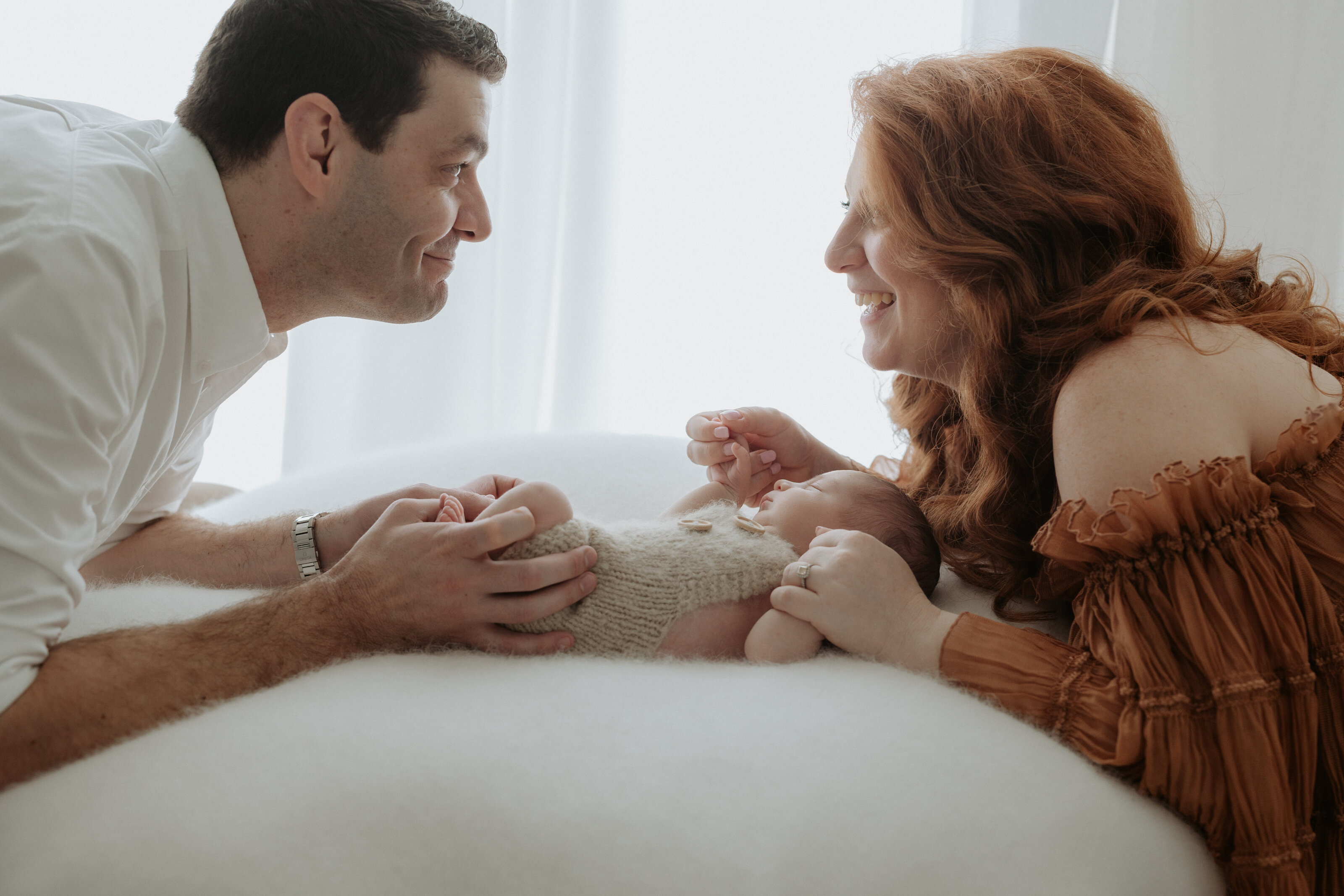 Tender family cuddle with their newborn in a warm indoor setting in Perth