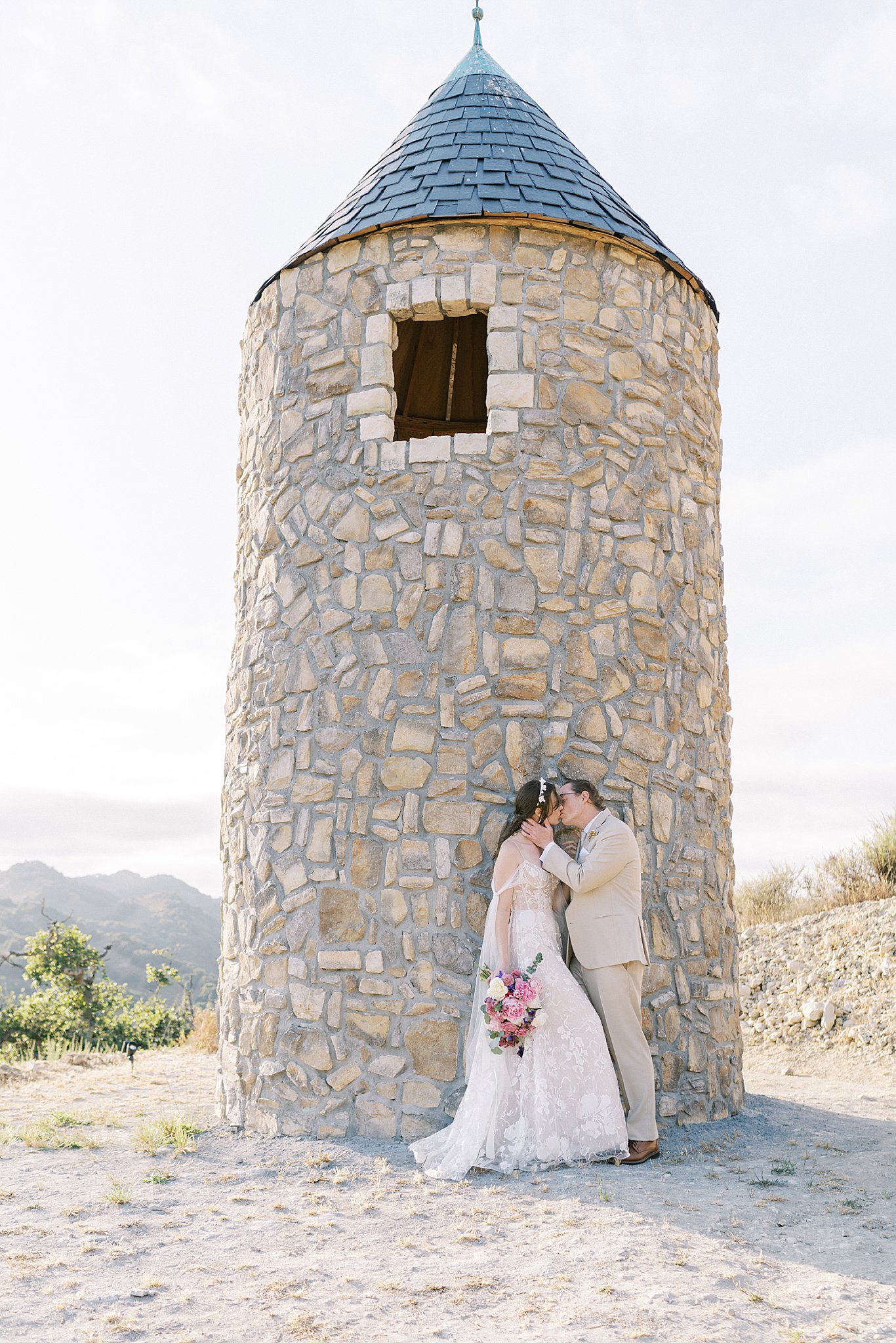 bride and groom kiss in their wedding attire at chateau noland in san luis obipso.