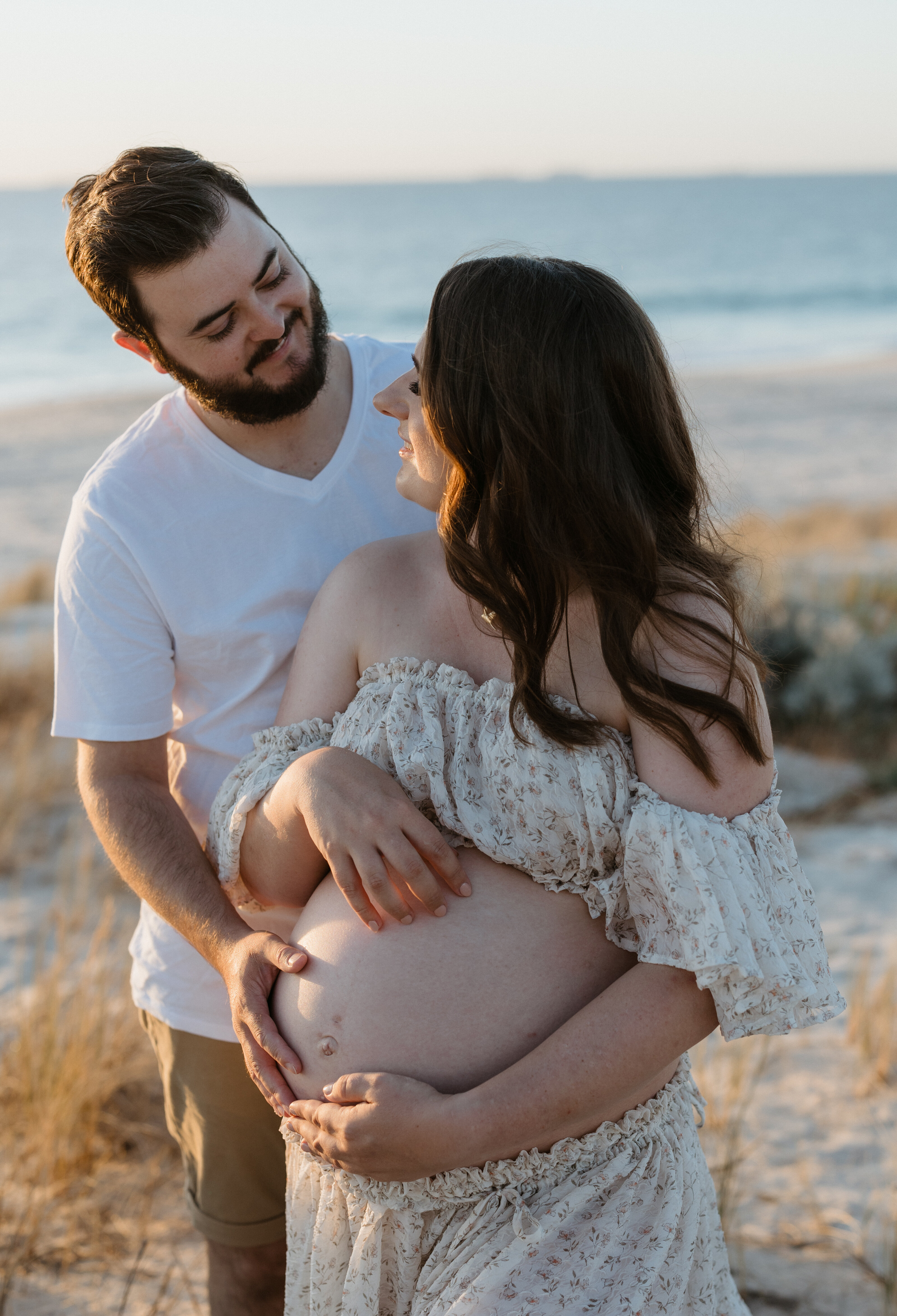 Expecting parents sharing a warm embrace in an outdoor maternity session in Perth
