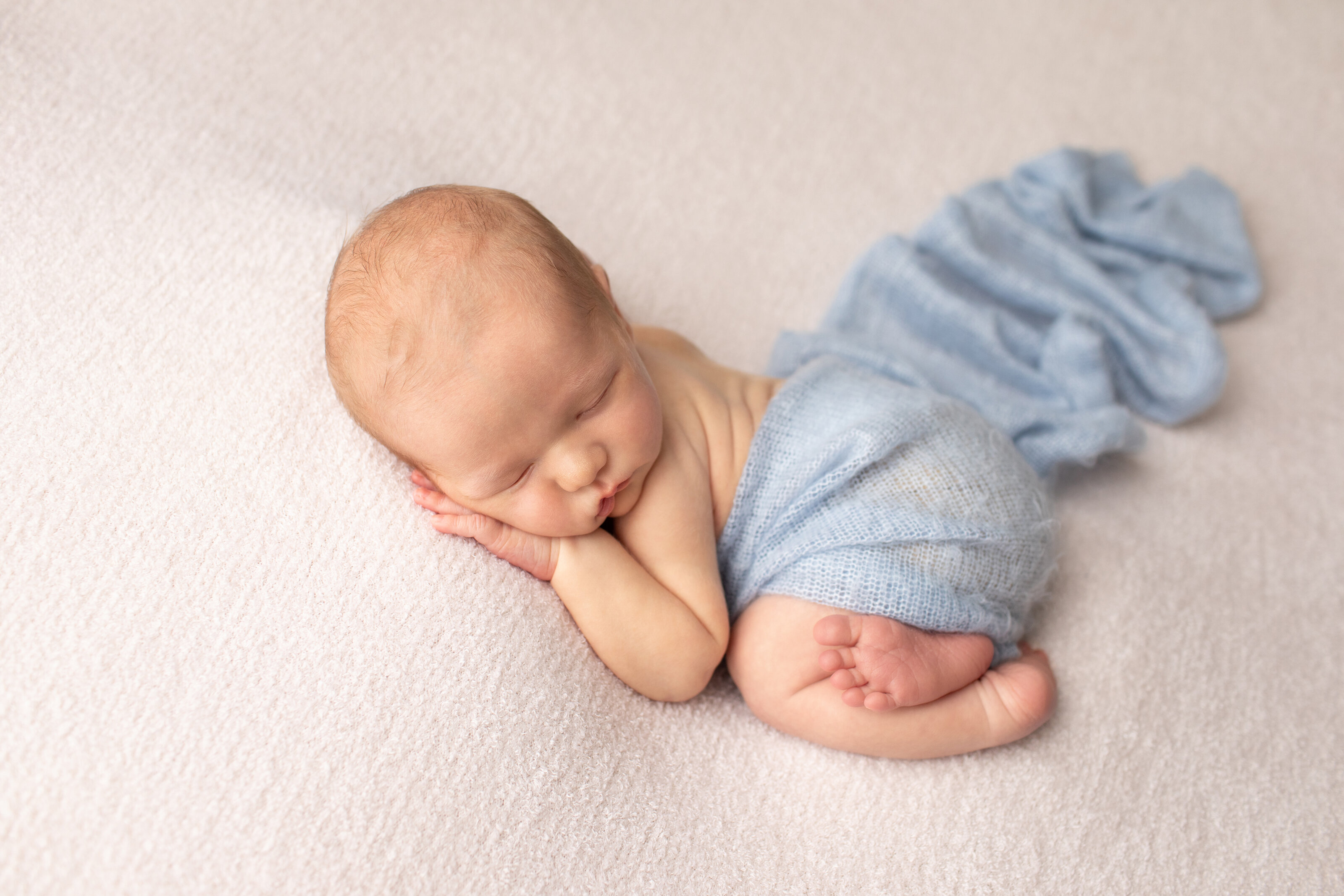 Newborn boy in tummy pose with light blue fabric