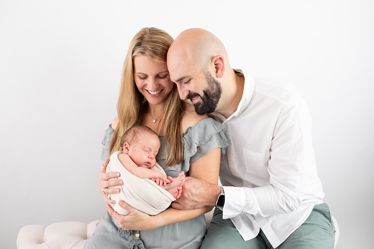 Parents cuddling new baby in studio by Baltimore Newborn Photographer