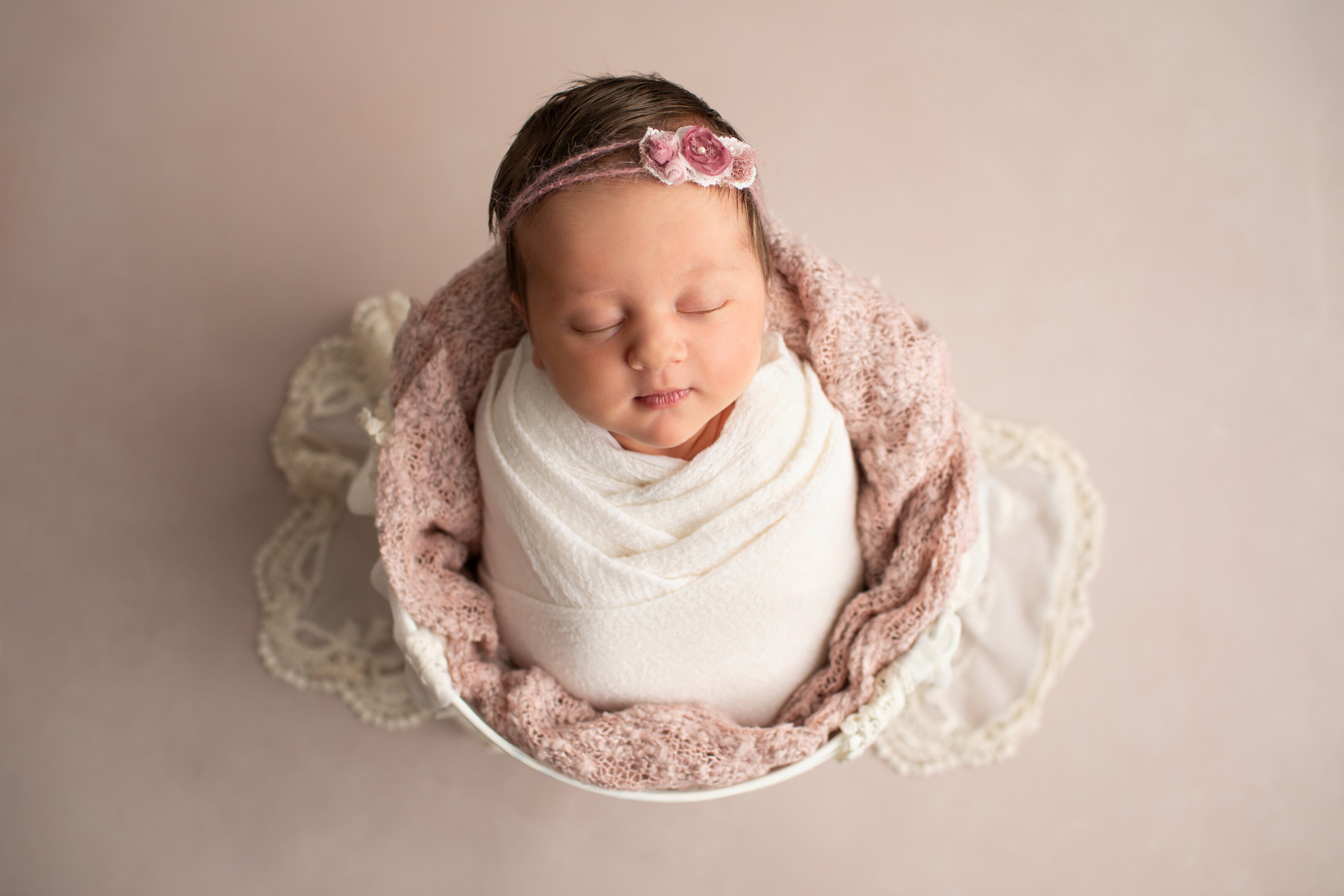 newborn girl in cream color wrap and decorative headband