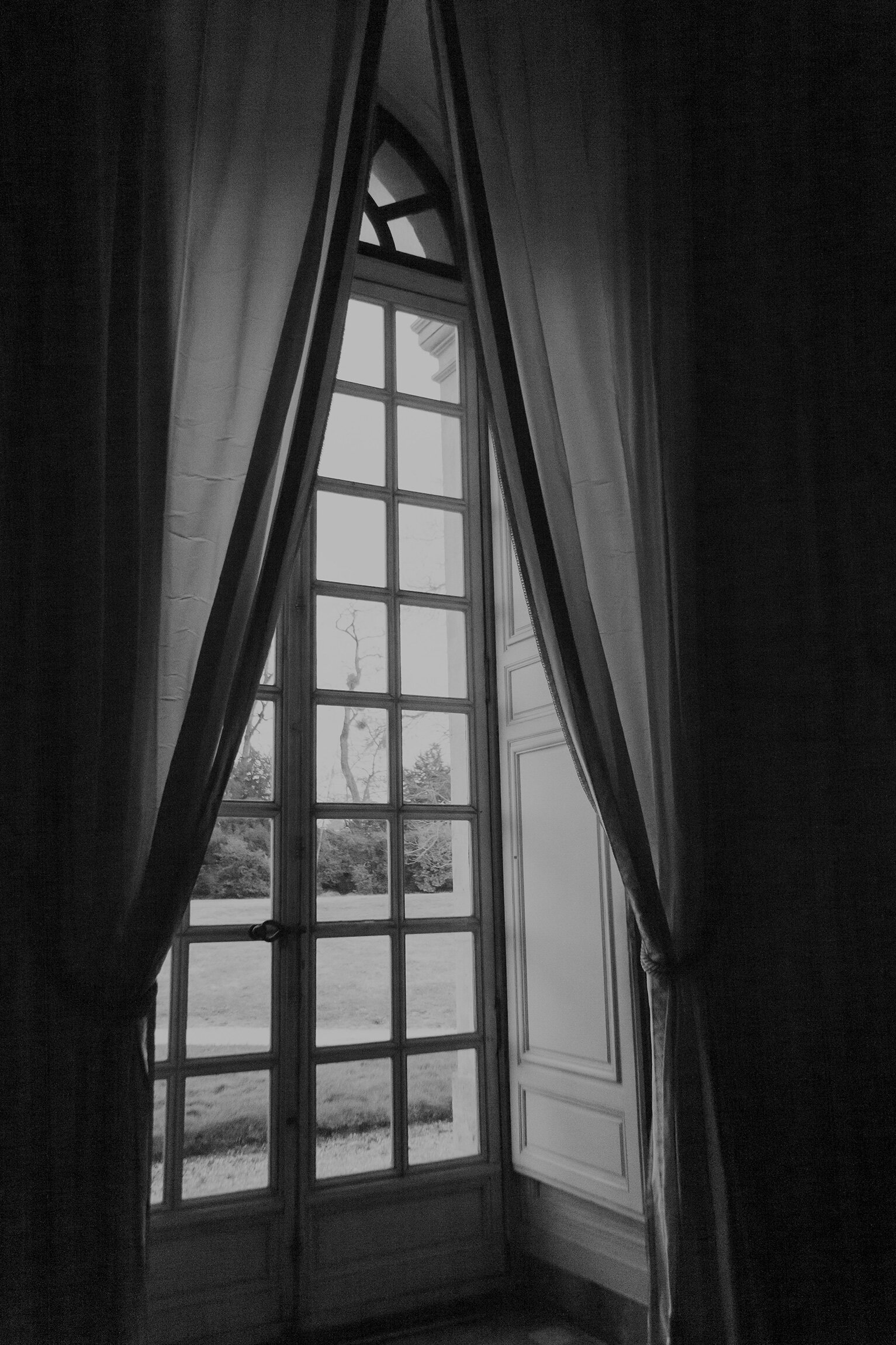 Dramatic black and white photo of window with tall curtains
