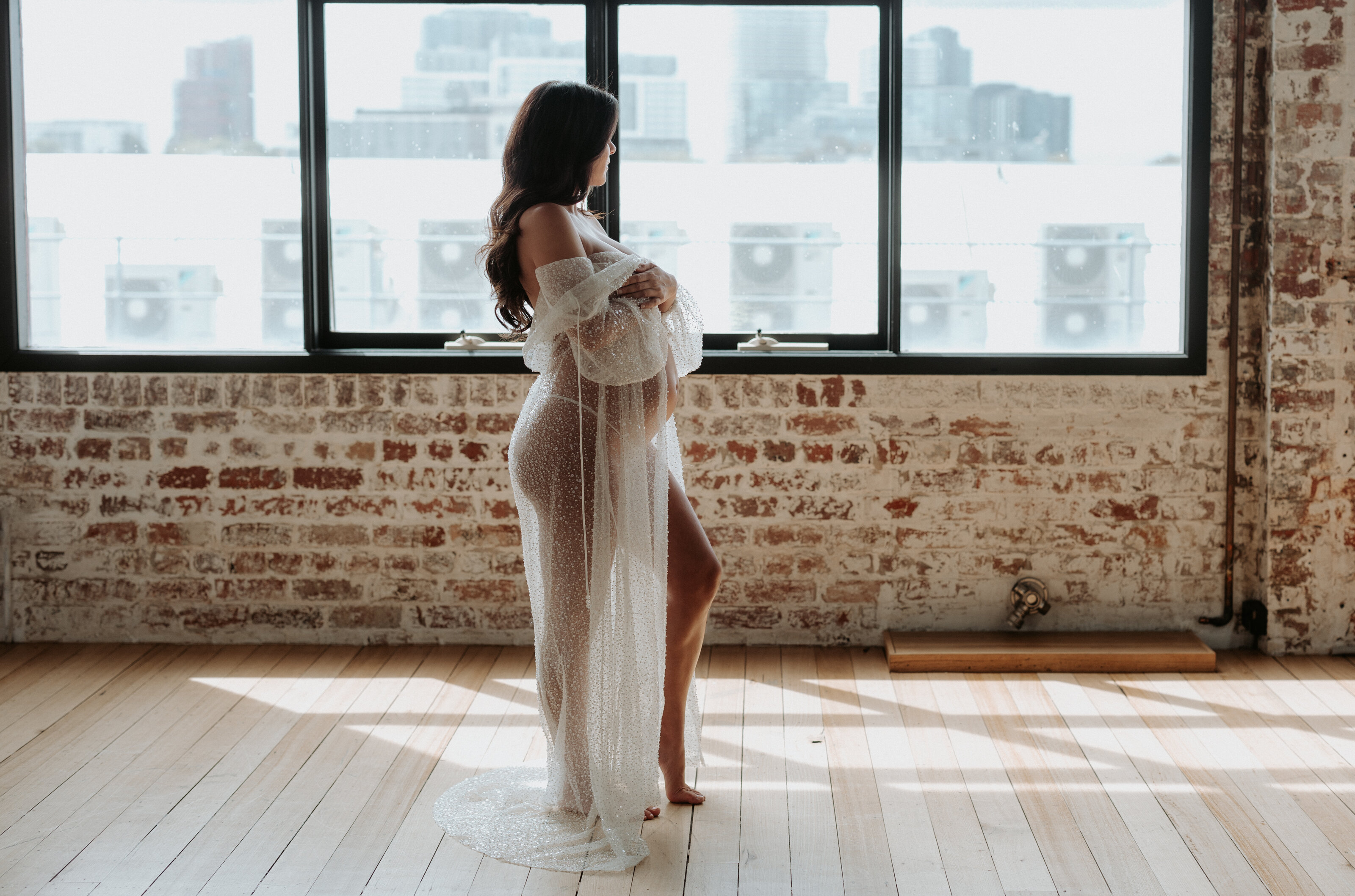 Pregnant woman in a flowing dress during indoor maternity session in Perth