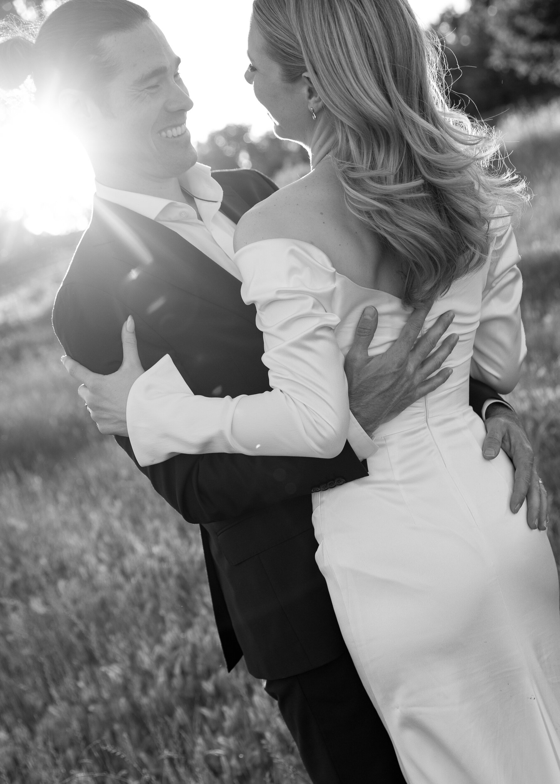 A newly wed couple embrace and smile at one another in their wedding attire