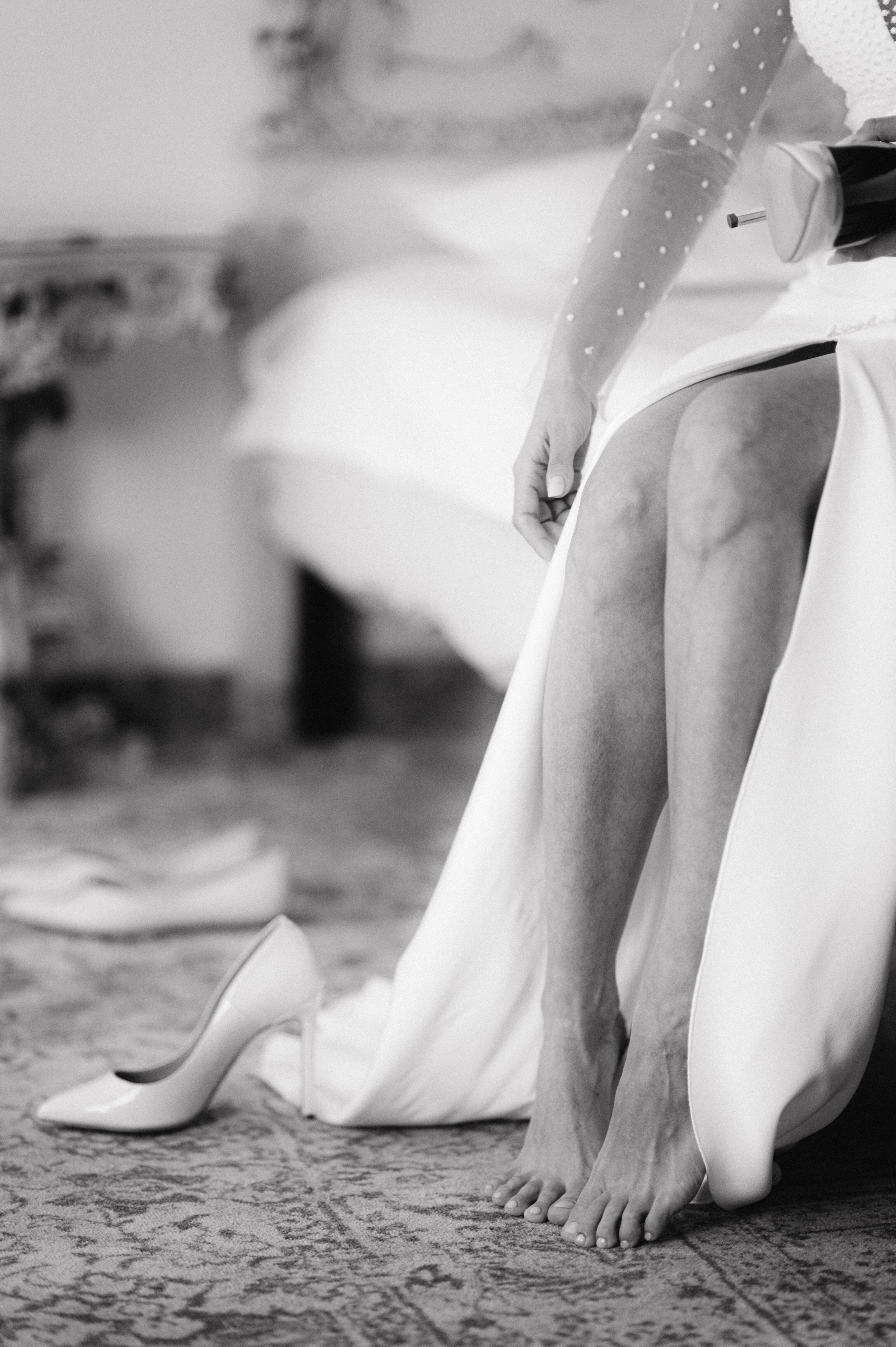 Bride putting on her wedding day shoes, black and white photo