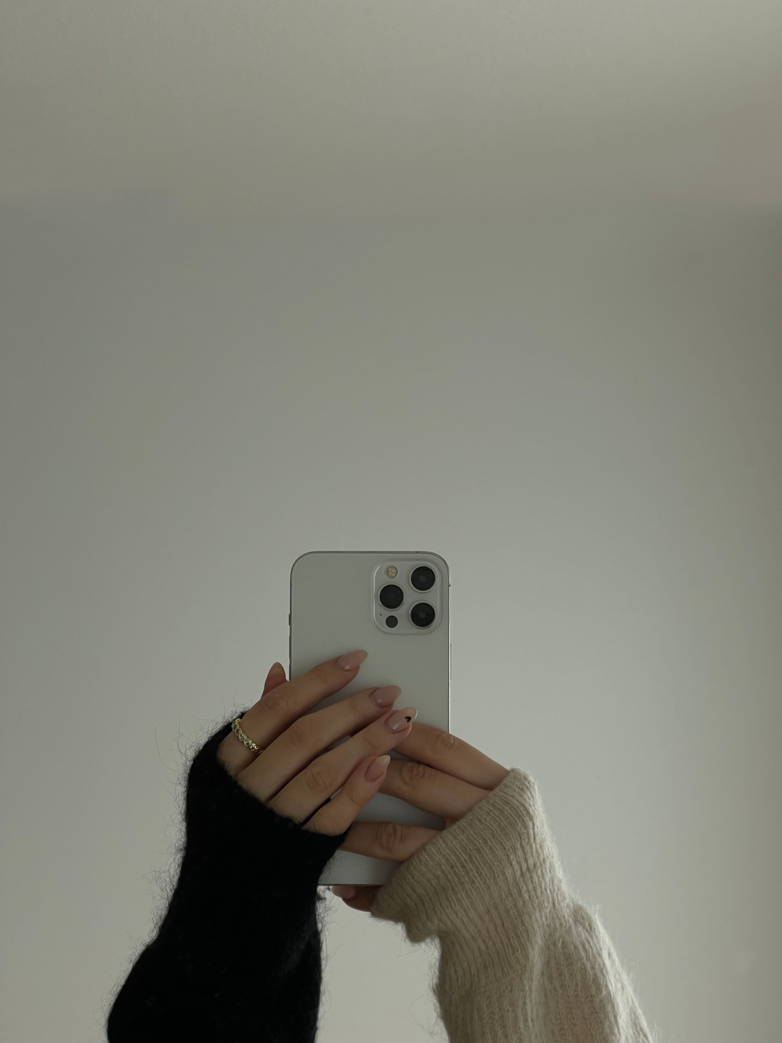 artsy photo of girls hands taking a photo on her phone of her phone in a reflection