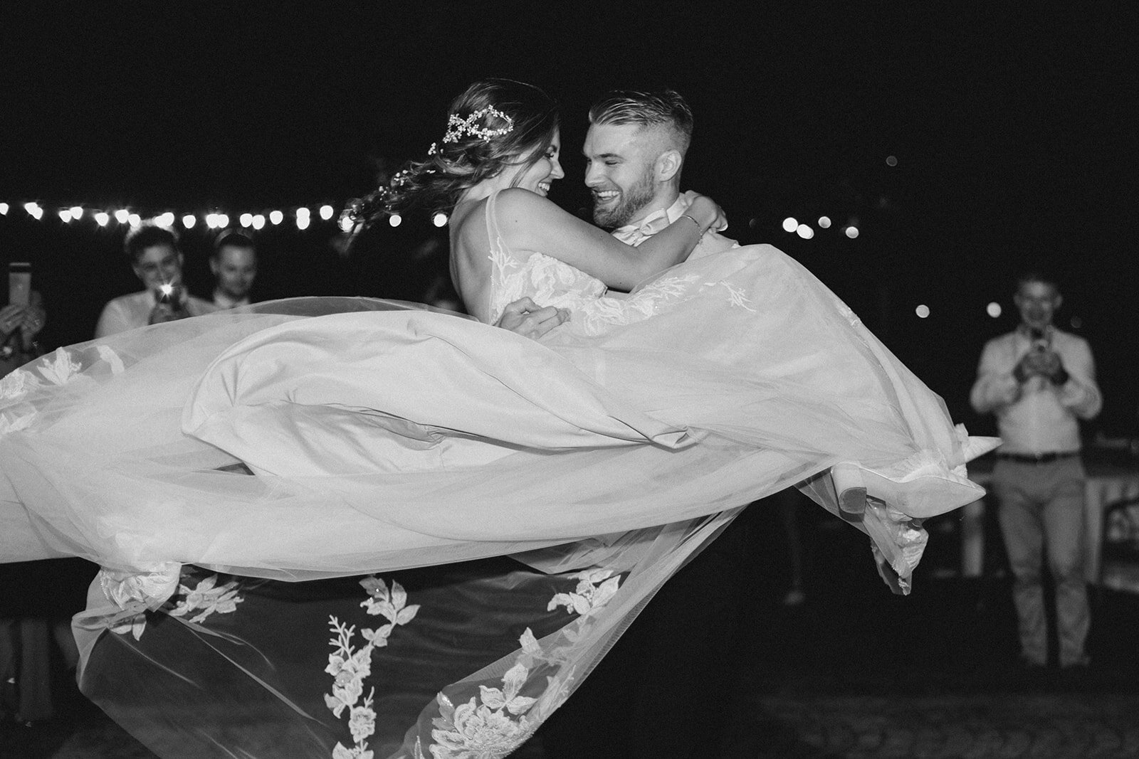 Groom dancing with his bride in his arms at their wedding reception