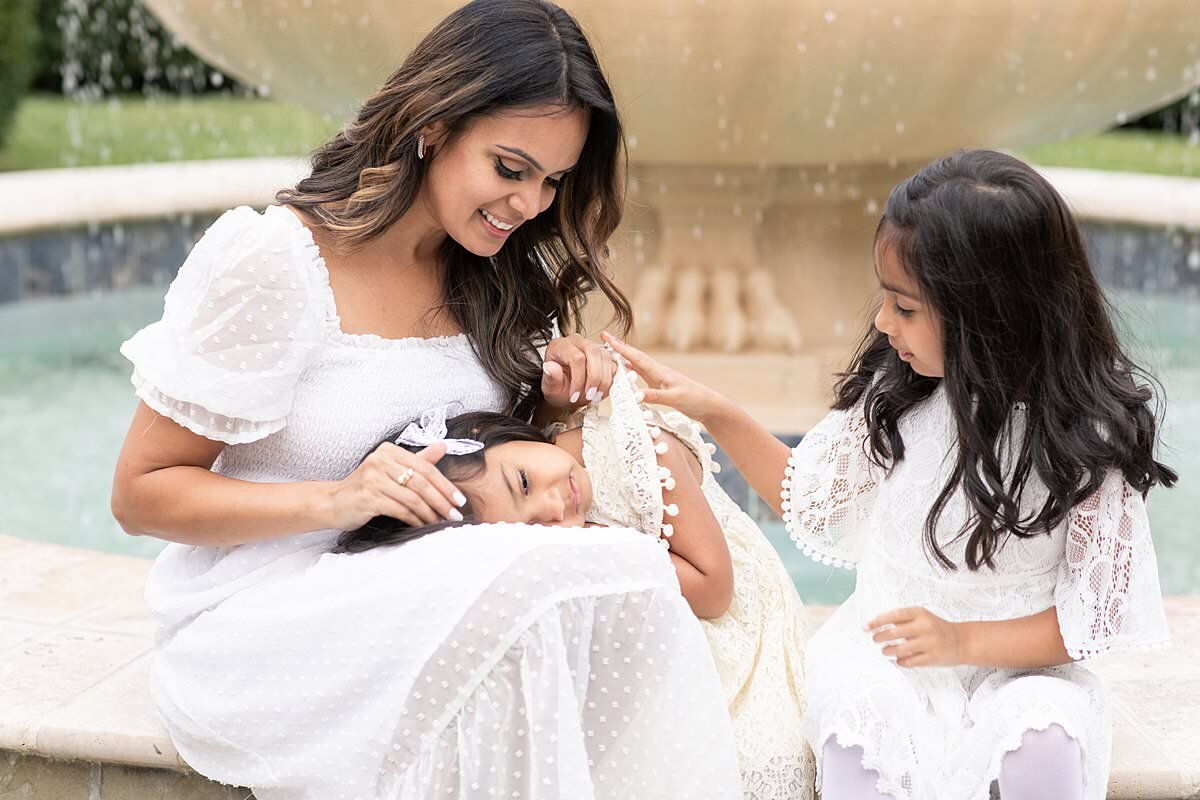 Mom sitting by fountain with 2 daughters by Maryland Family Photographer