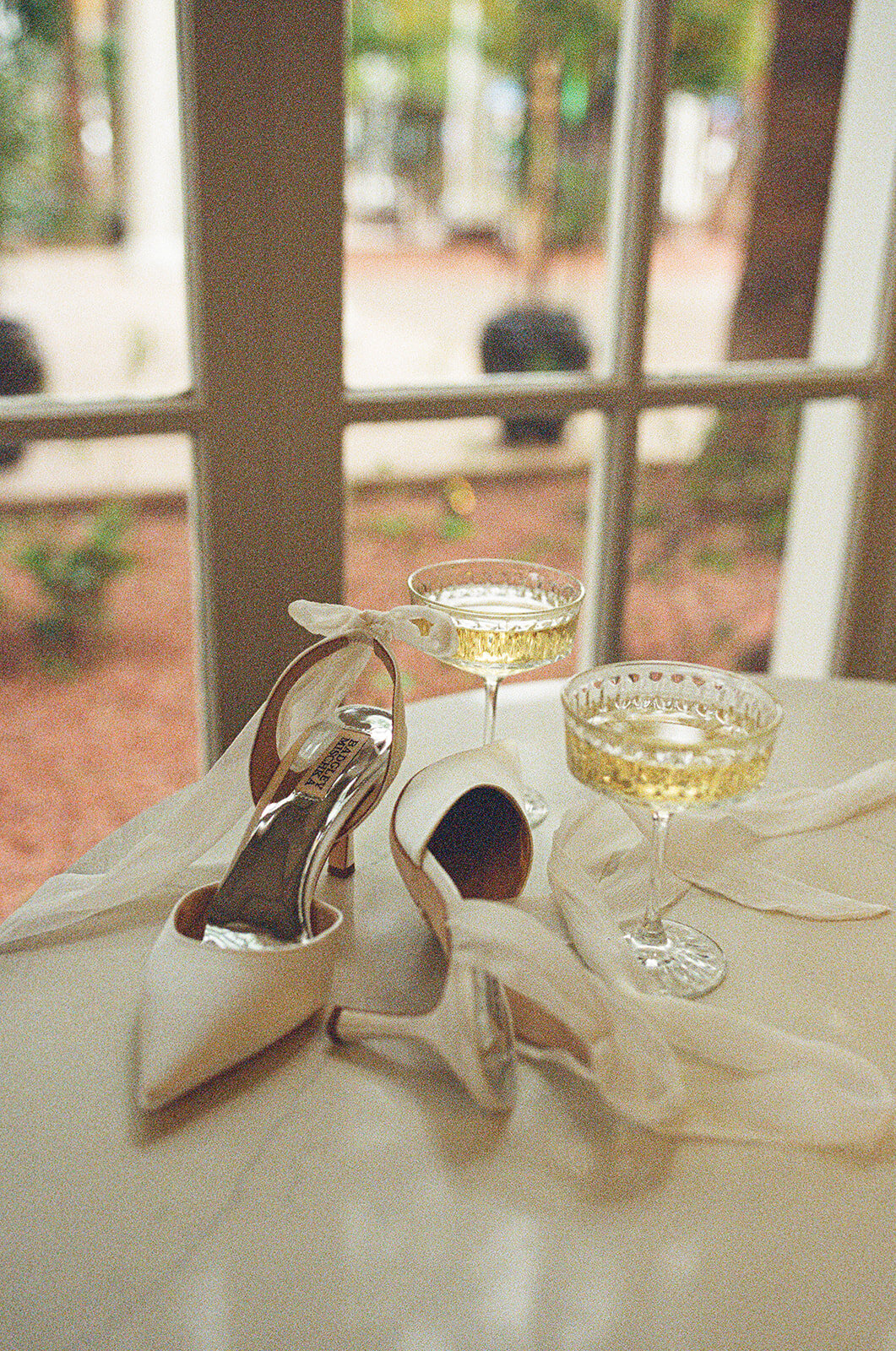 a pair of heels sit ona  table next to two full champagne flutes
