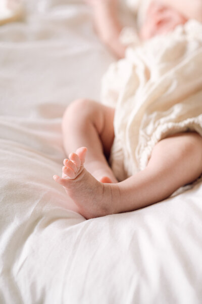 Close-up of newborn baby’s tiny feet on soft bedding during a lifestyle session, photographed by a Northern Virginia family photographer.